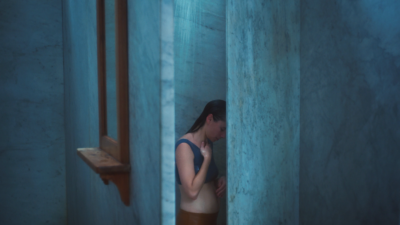 En kvinne i undertøy står i en offentlig dusj