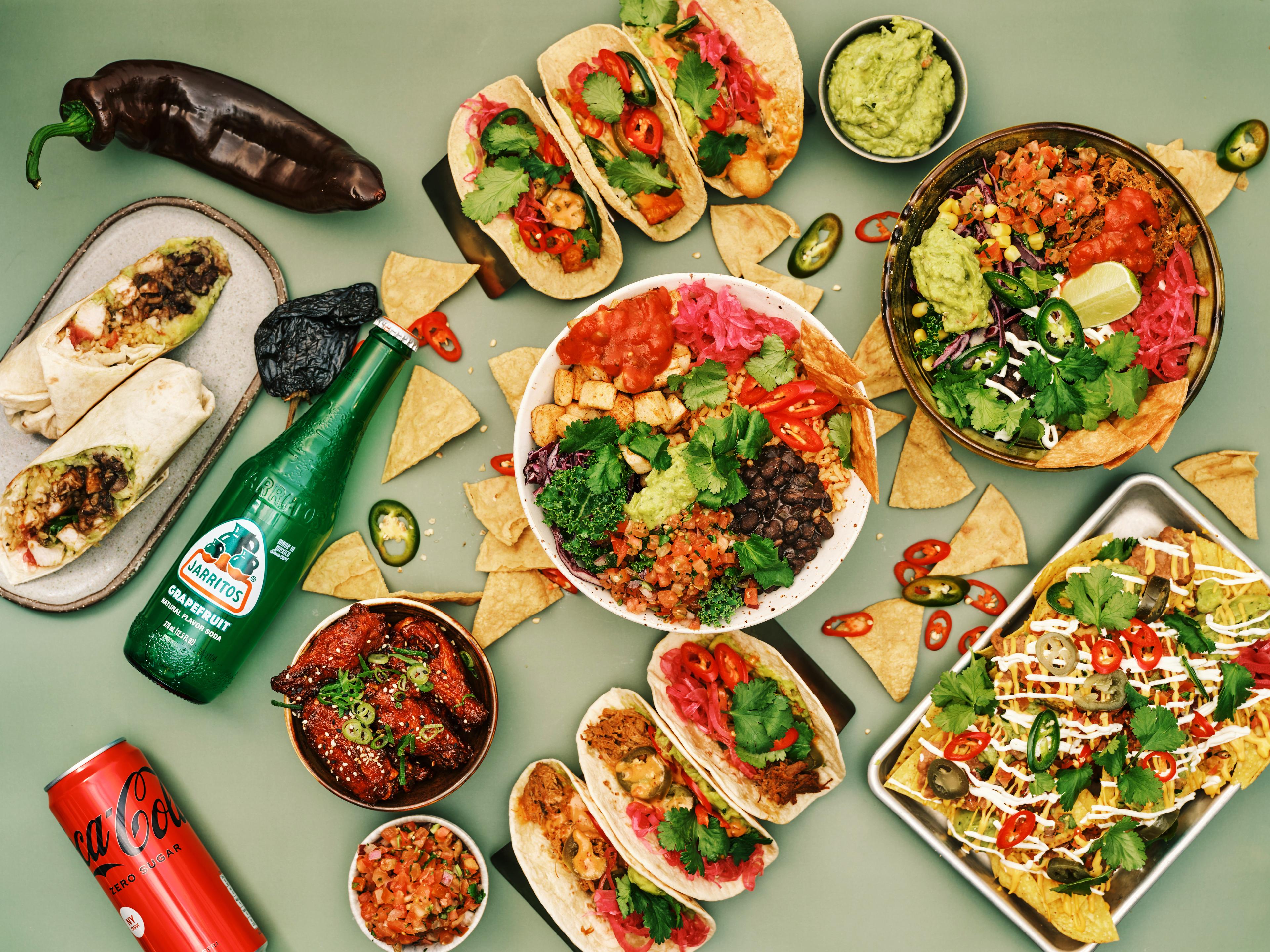 Image of a Mexican feast with nachos, tacos and burritos on a green background