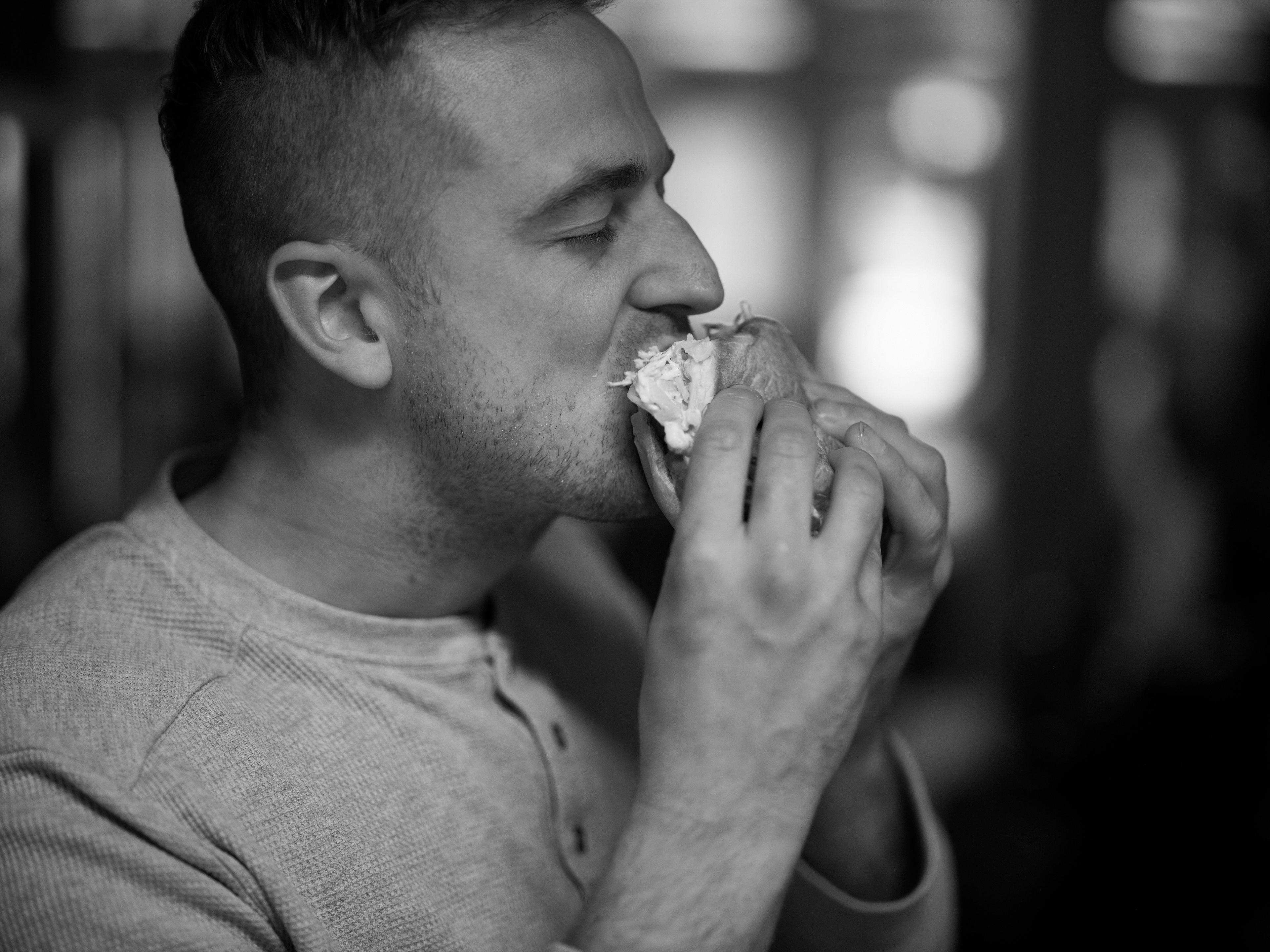 Black & white image of a man eating a hamburger