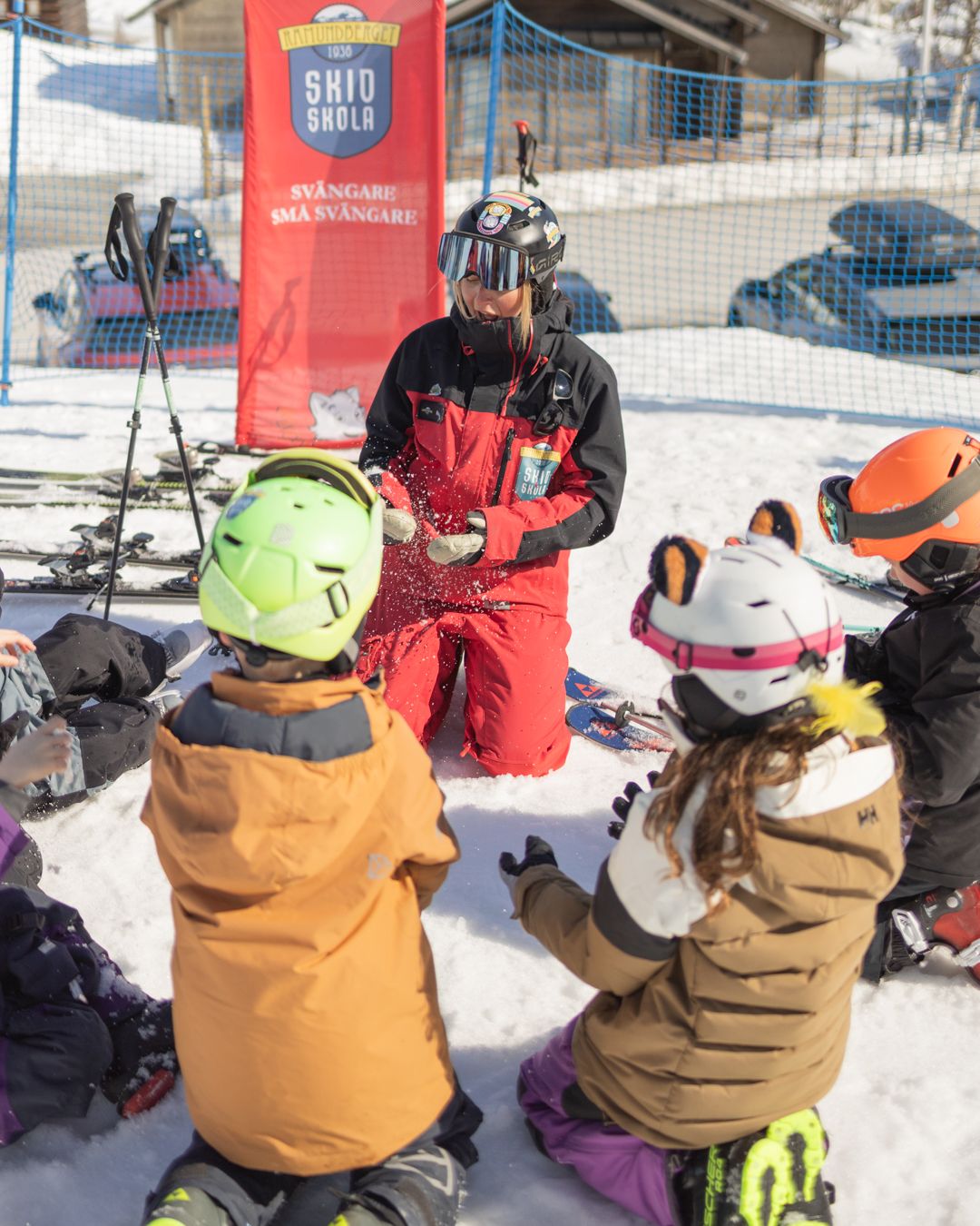 En grupp barn som sitter på den snötäckta marken.