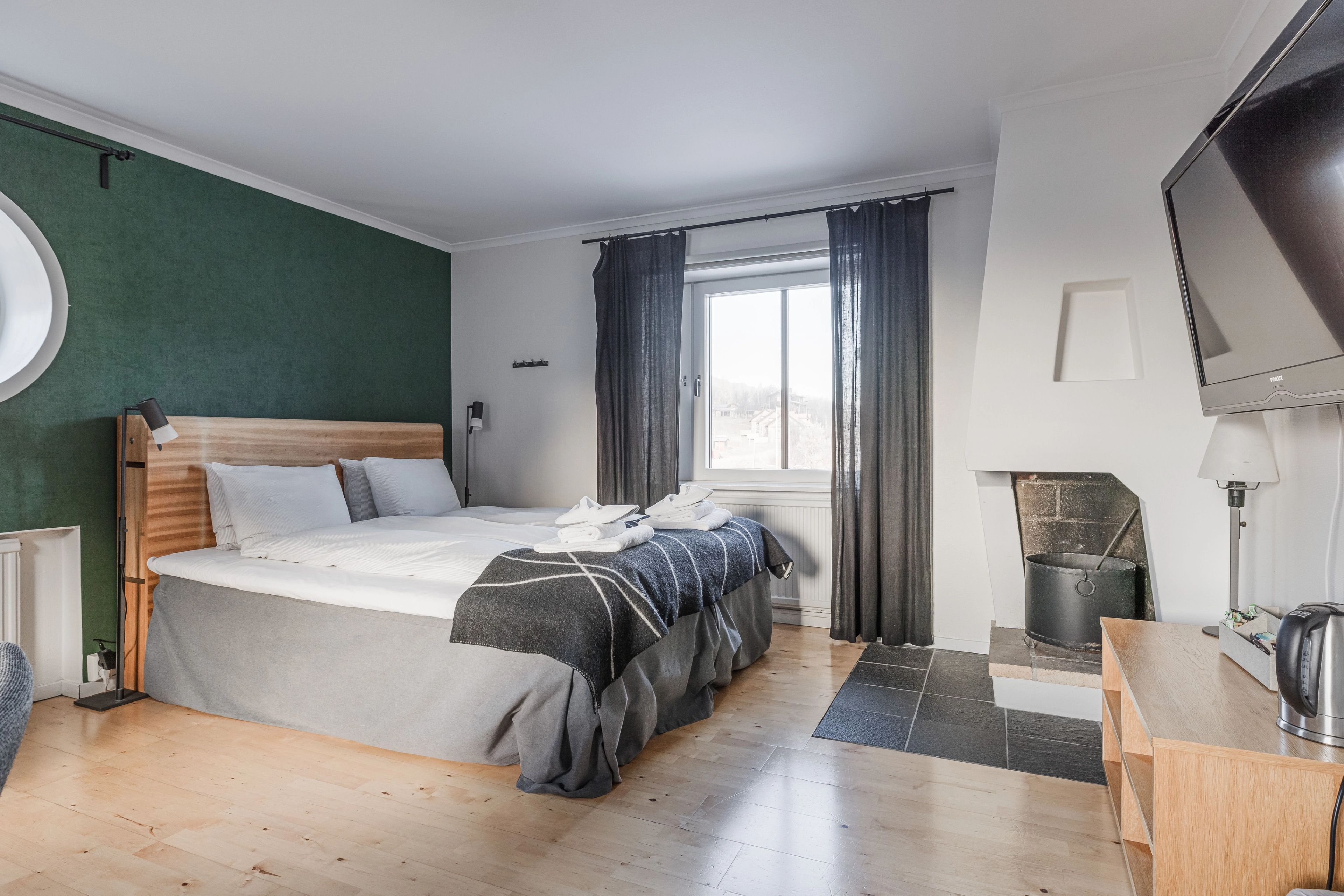 Ett hotellrum i Ramundbergets Fjällgård med en stor säng och en platt-tv och en braskamin.