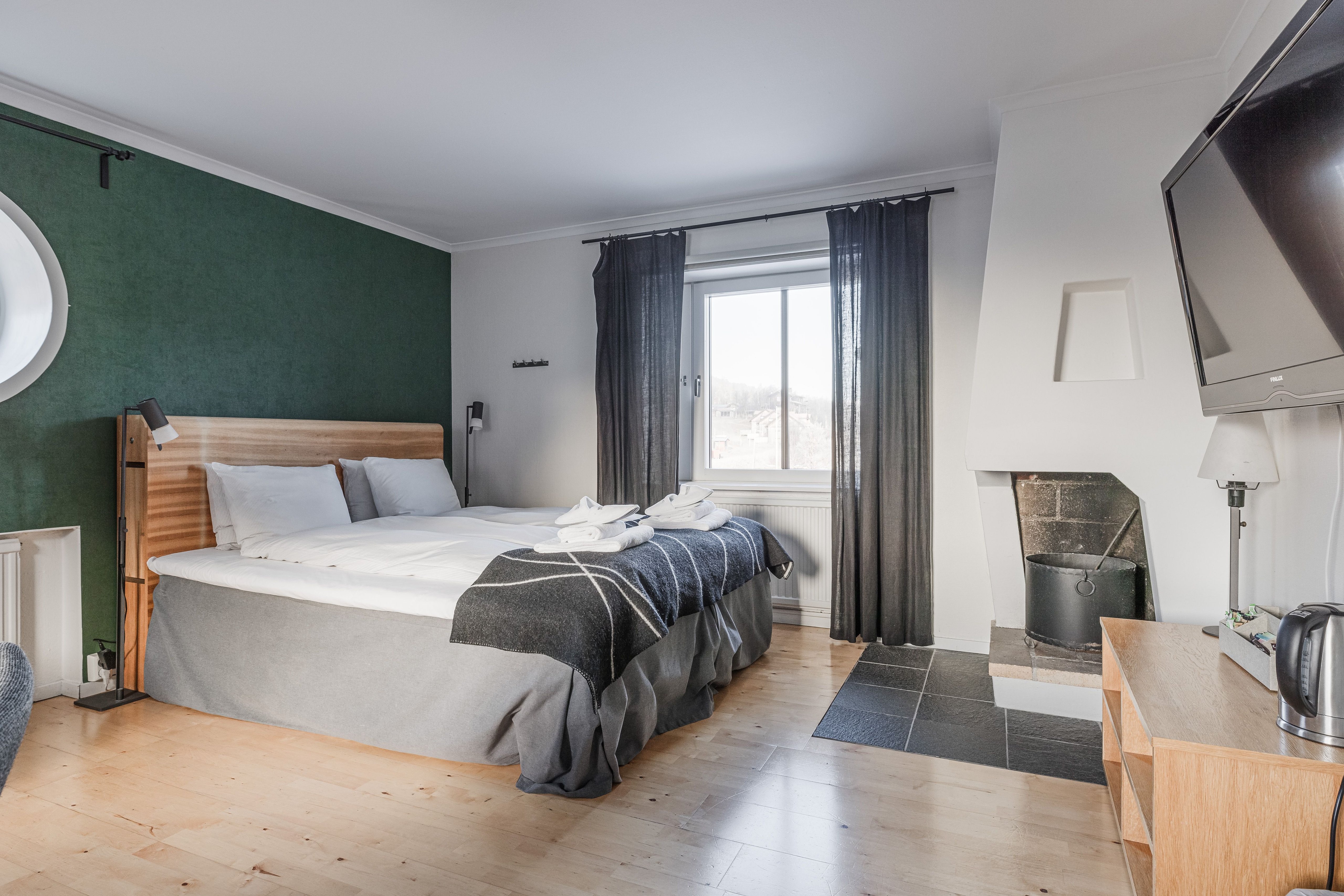 Ett hotellrum i Ramundbergets Fjällgård med en stor säng och en platt-tv och en braskamin.