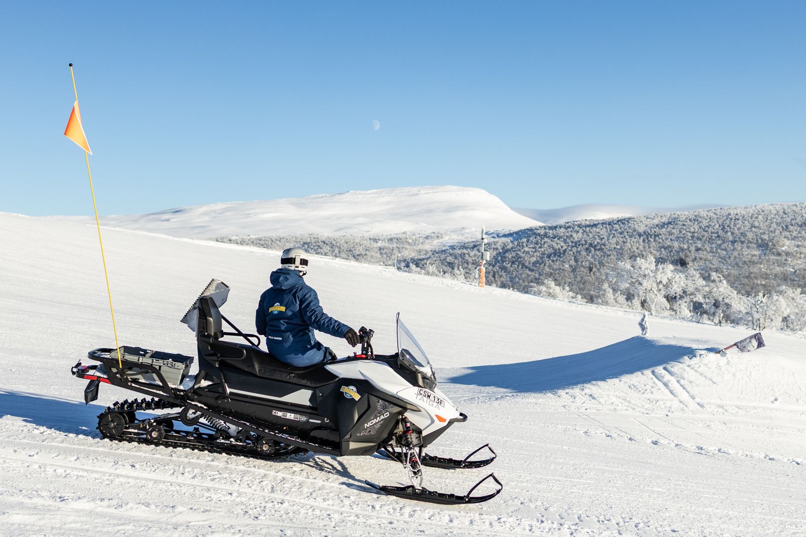En kvinna som kör snöskoter uppe på en snötäckt sluttning.