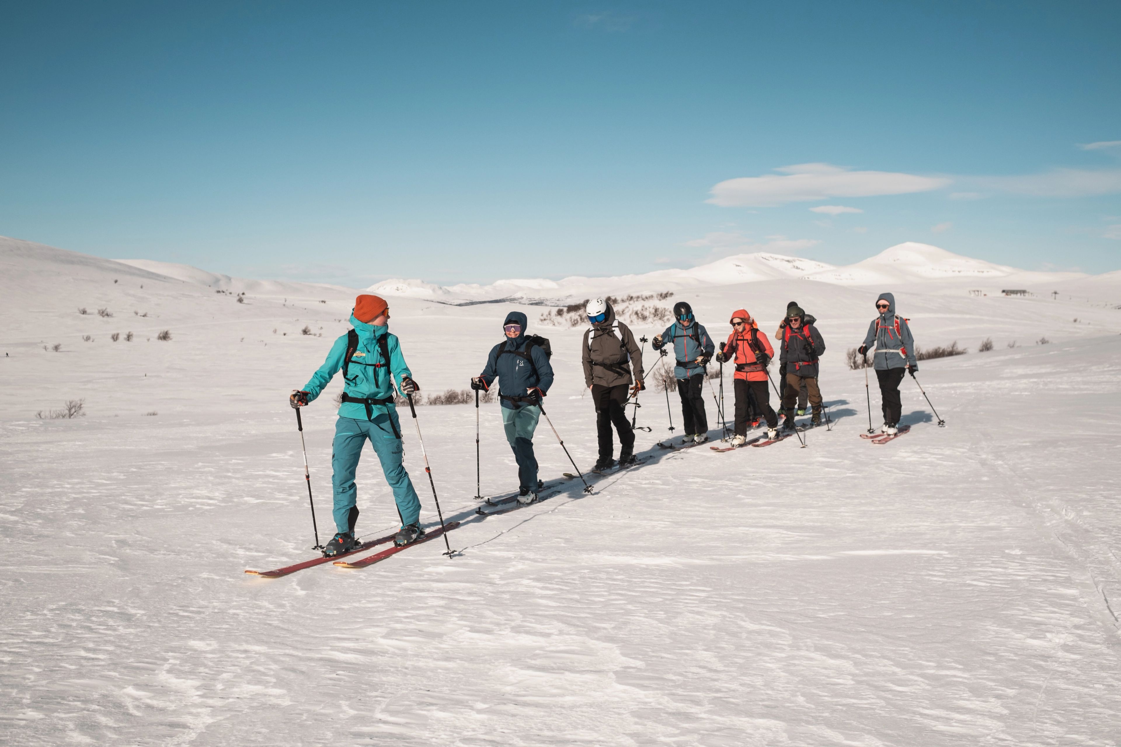 En grupp människor på skidor som står på toppen av en snötäckt sluttning.