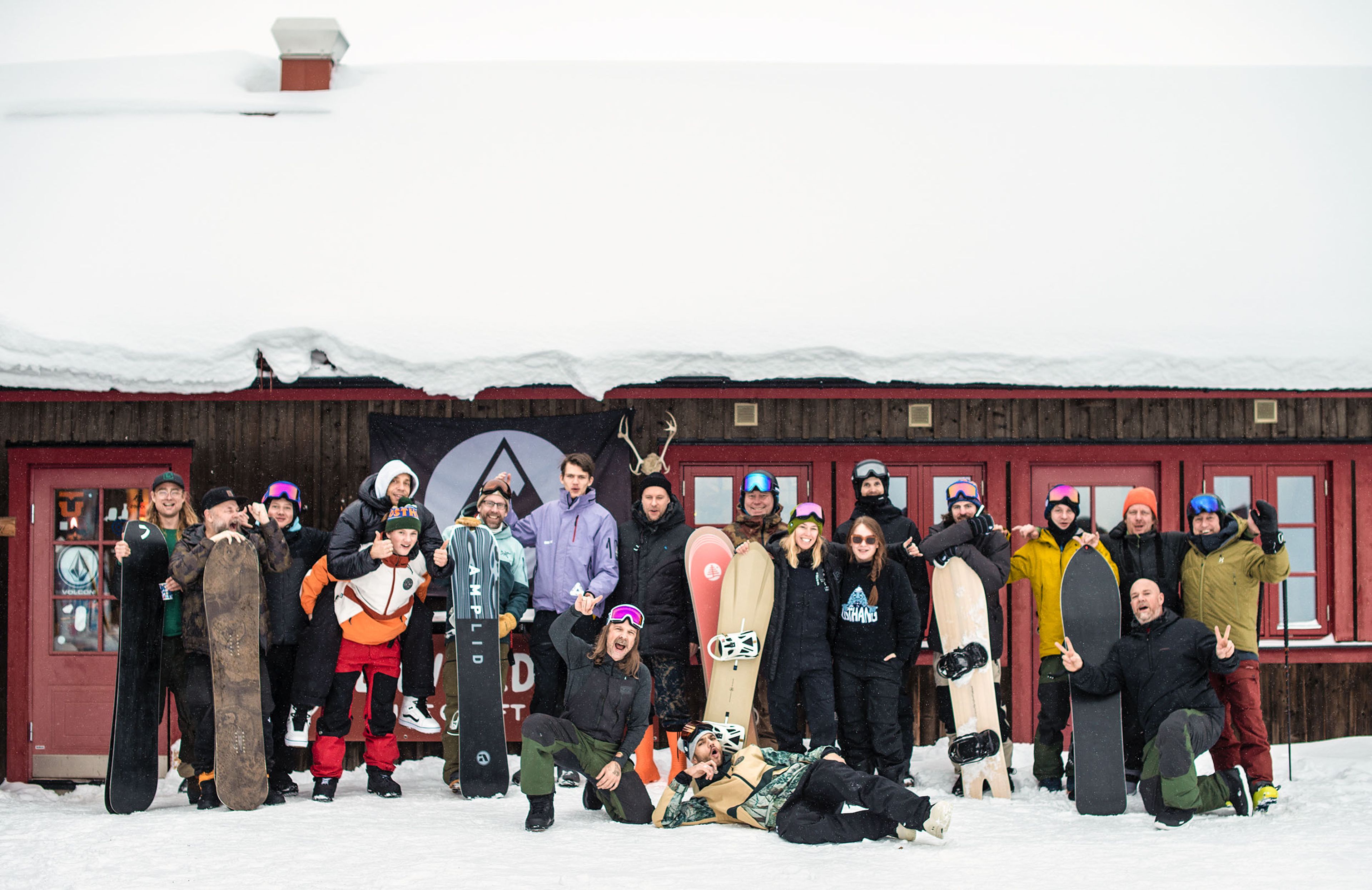 A group of people standing in the snow with their snowboards.