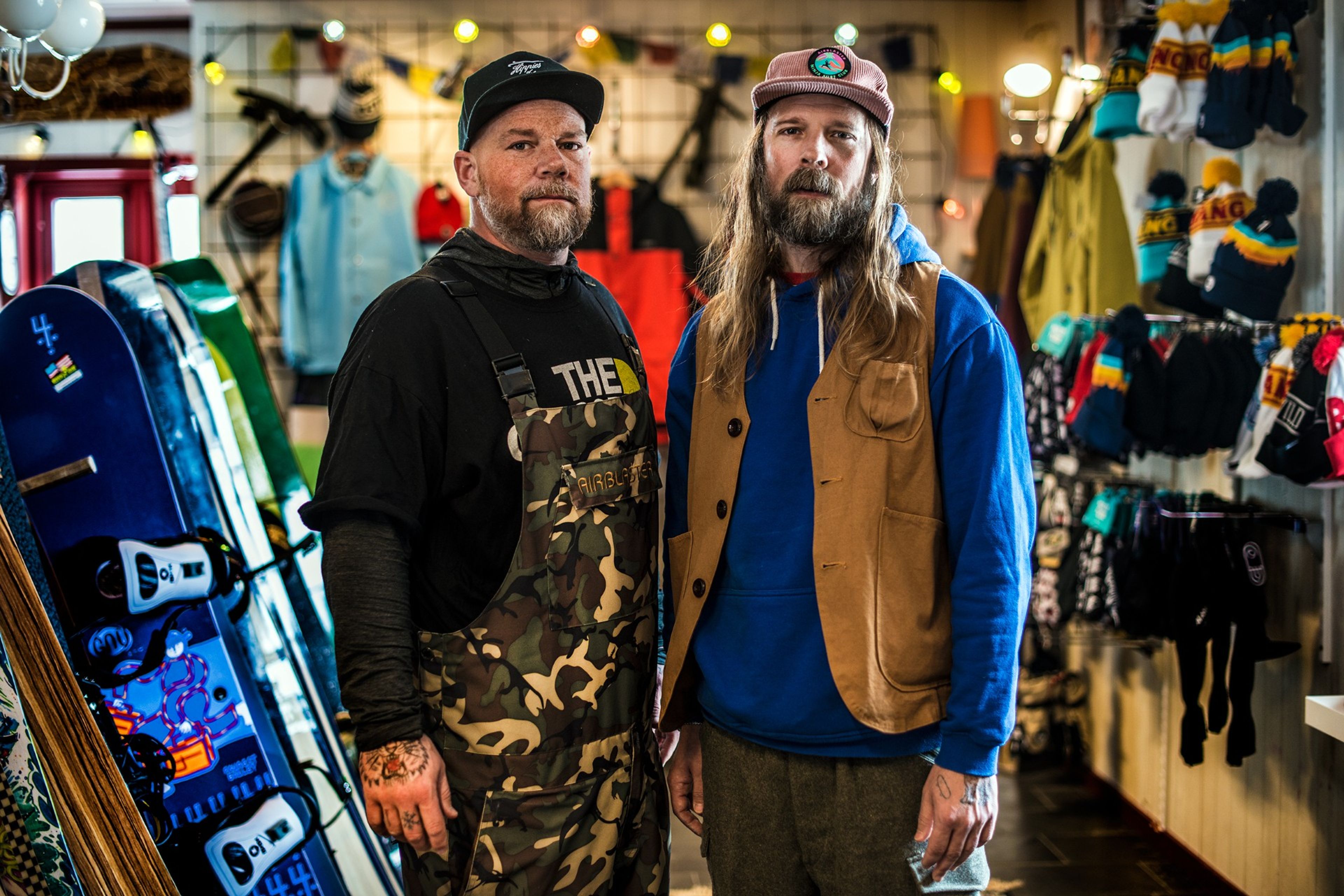 Two snowboarders standing next to each other in a sports shop.