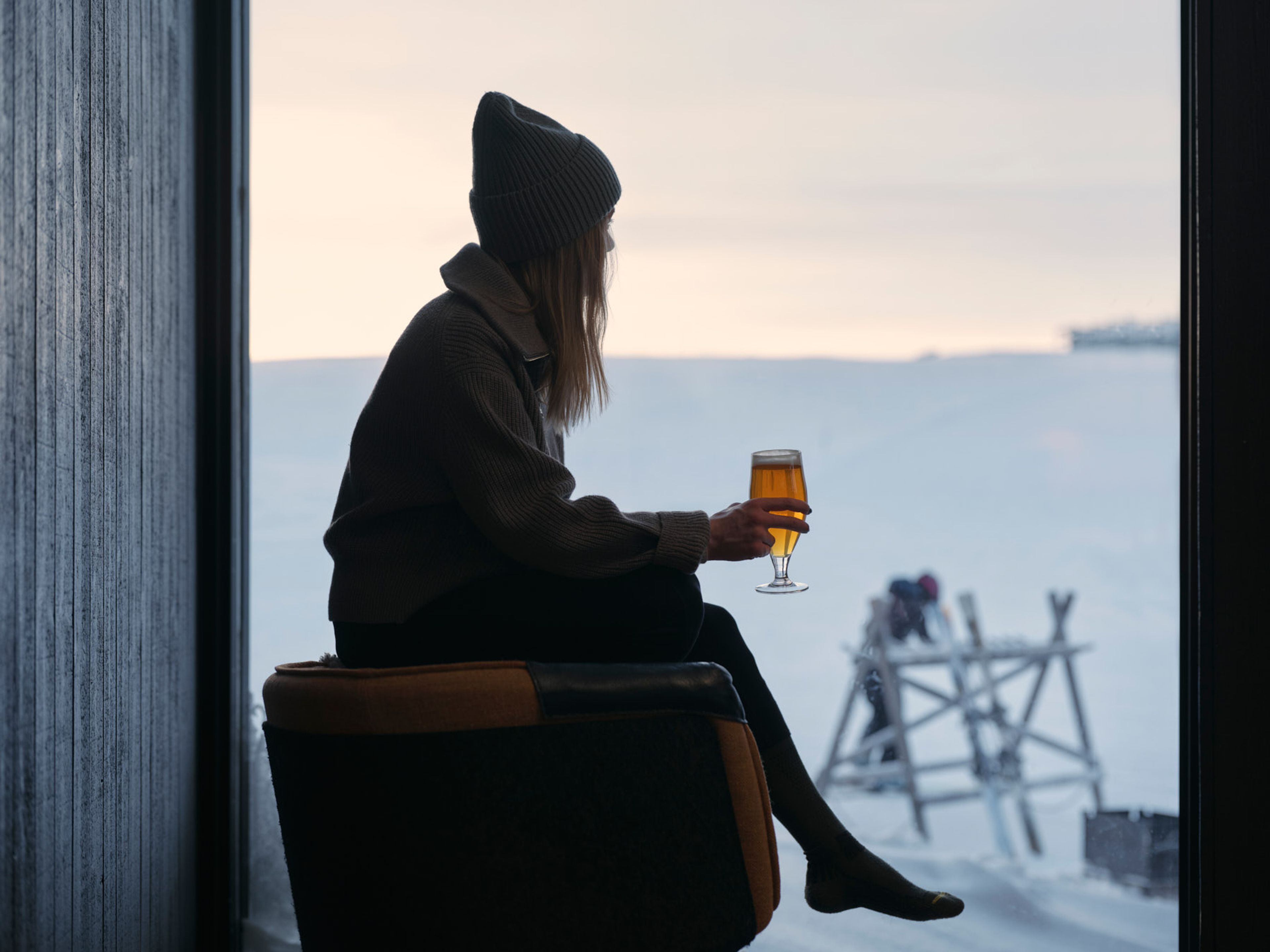 En person som sitter i en stol och håller ett glas öl.