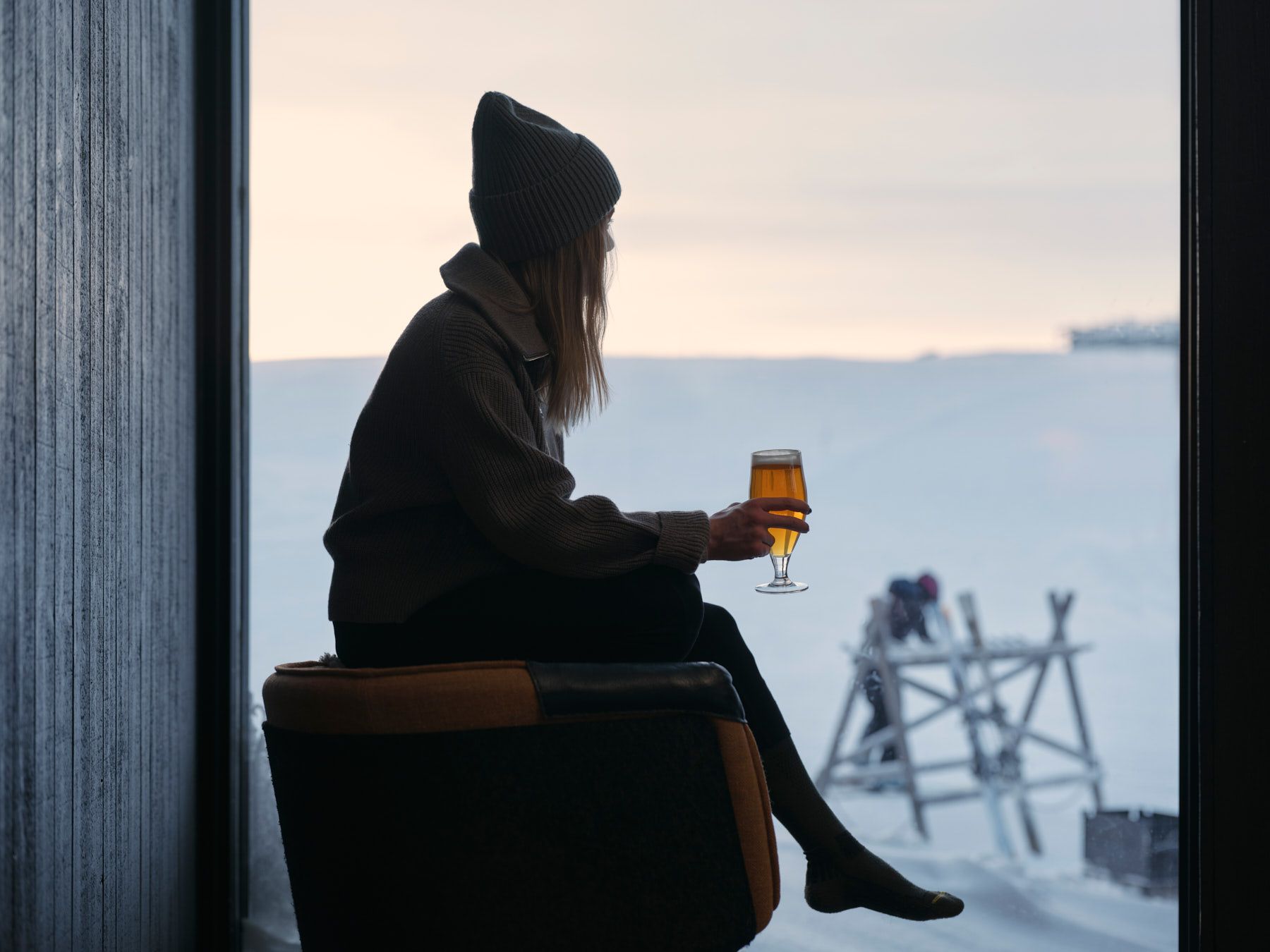En person som sitter i en stol och håller ett glas öl.