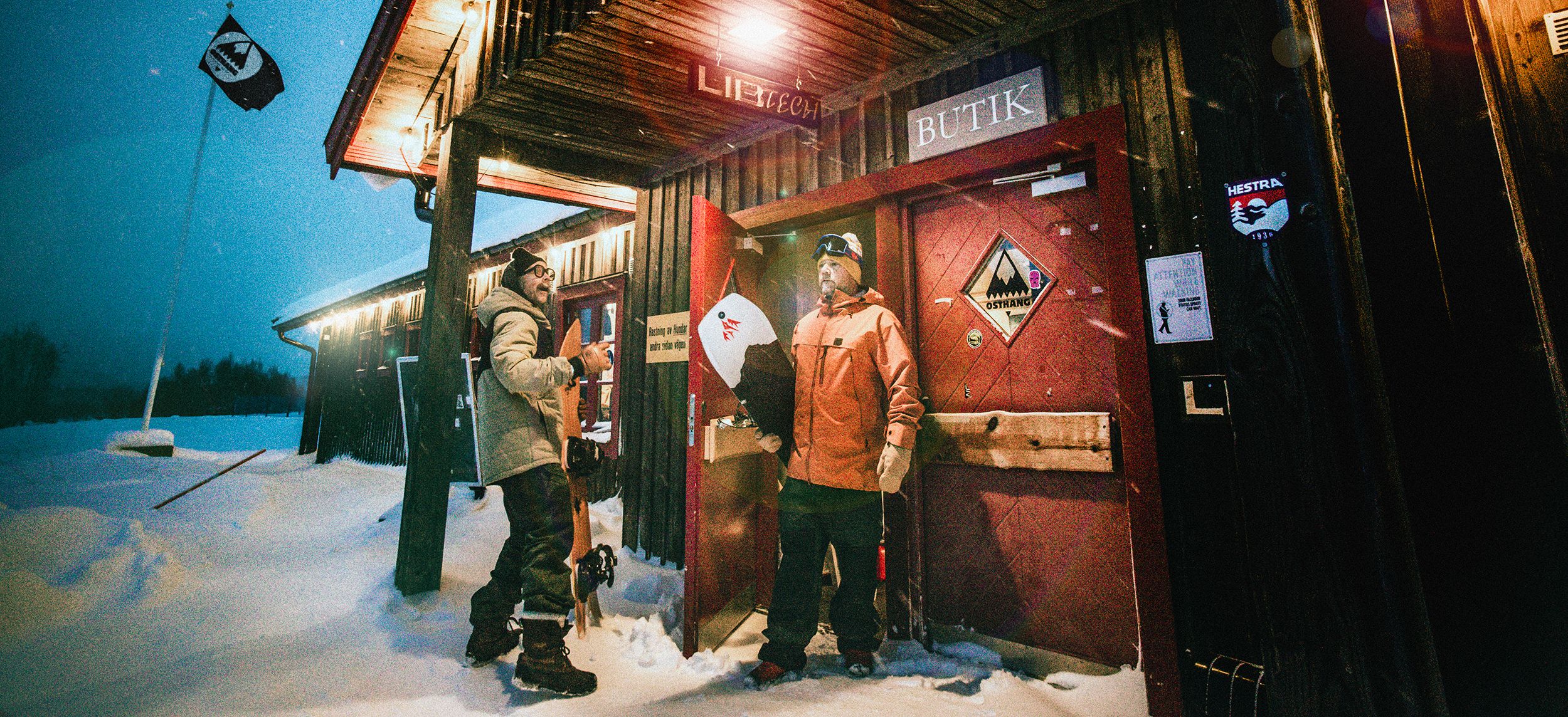 Two snowboarders standing outside a shop.