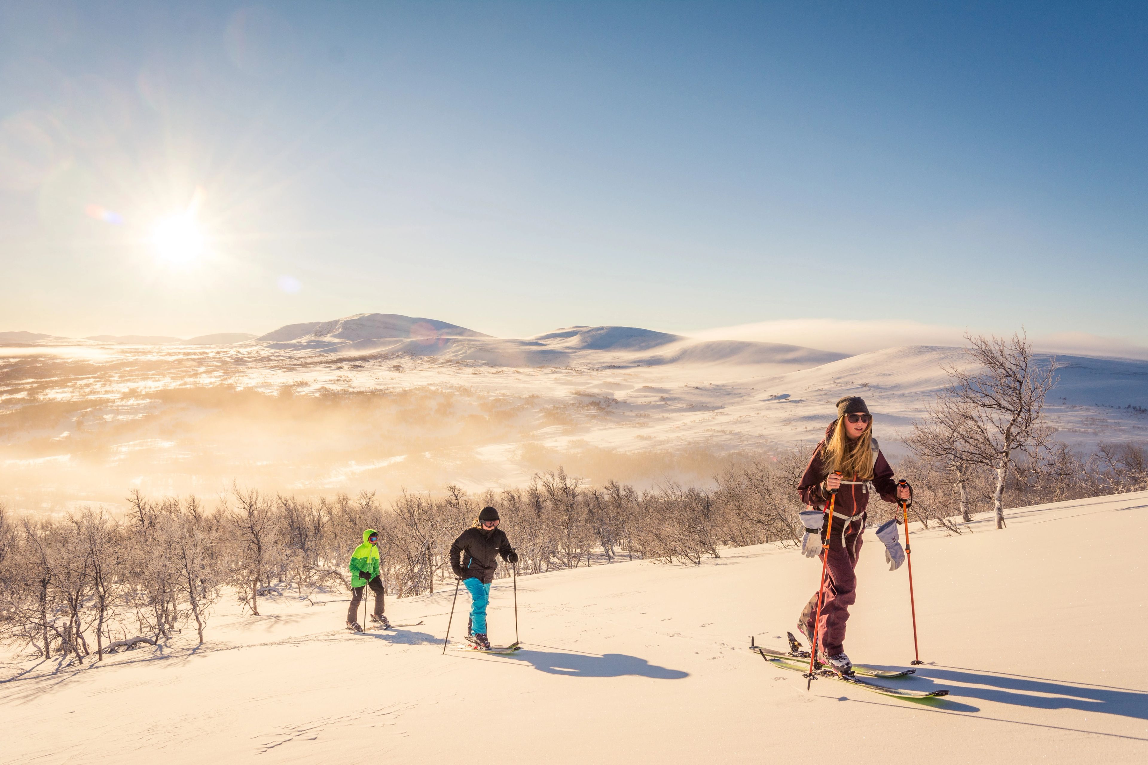 En grupp människor går på skidor upp för ett snötäckt berg.