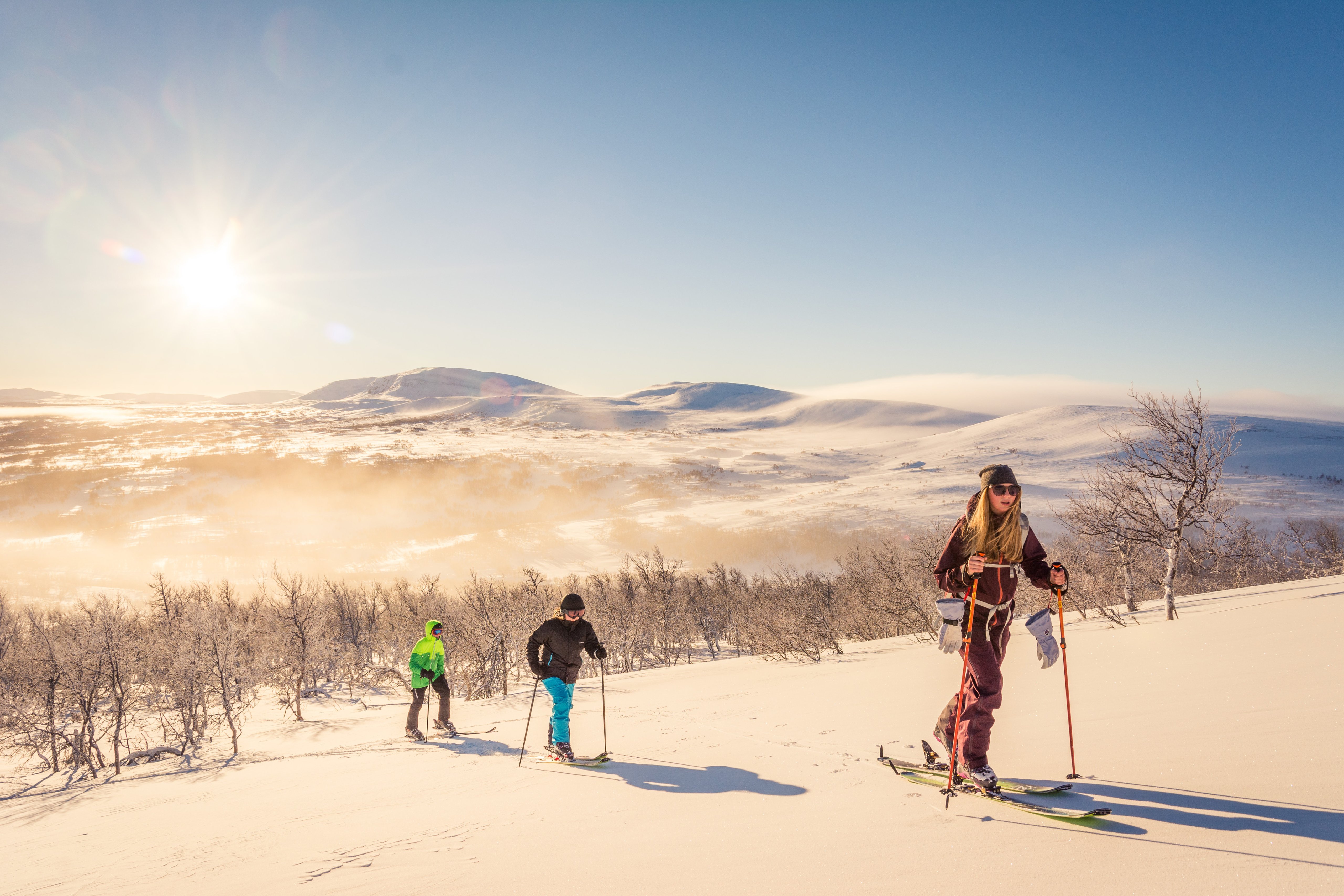 En grupp människor går på skidor upp för ett snötäckt berg.