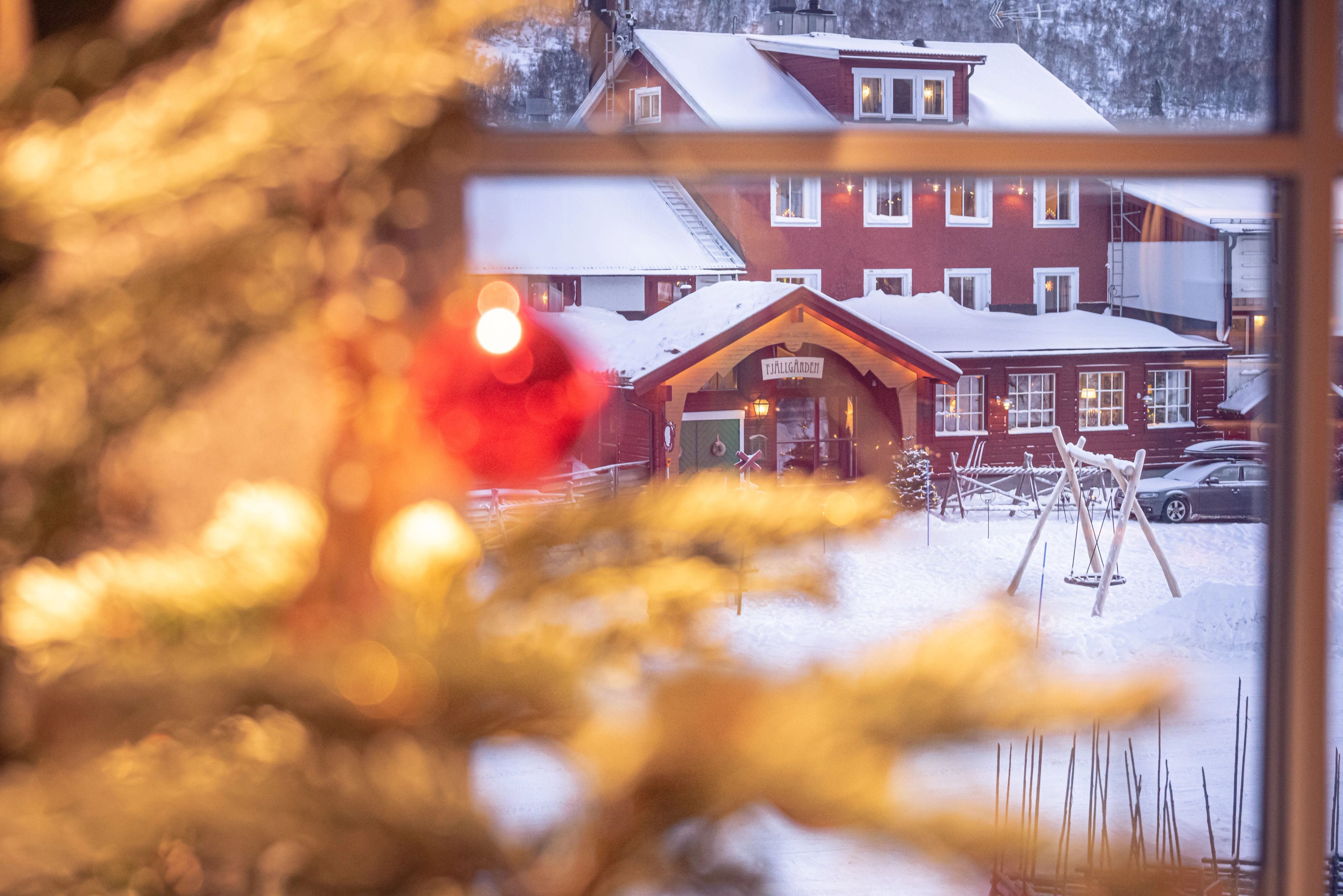 Utsikt över ett snöklätt hotell genom ett fönster.
