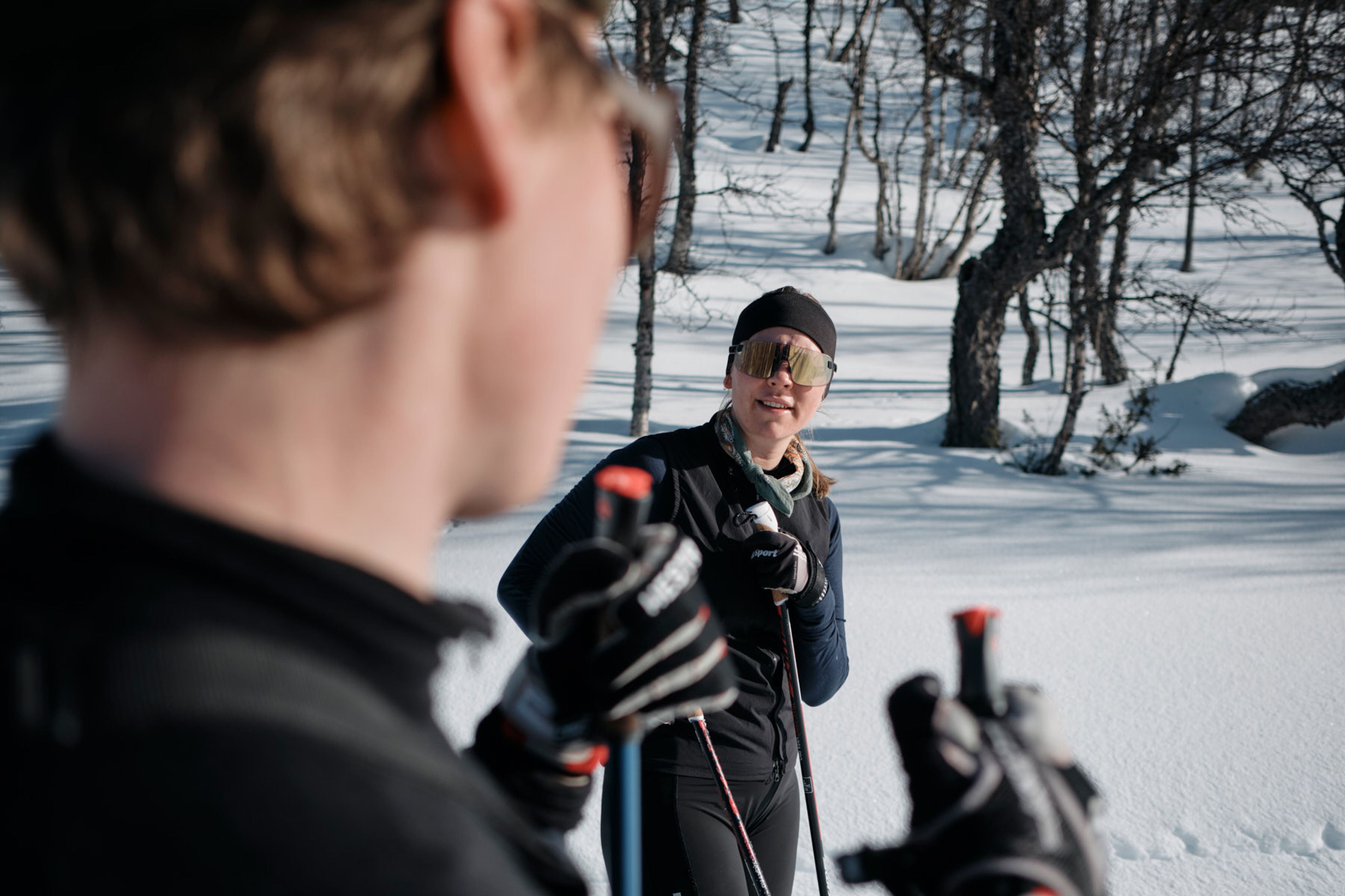 En kvinna som står bredvid en man på skidor.
