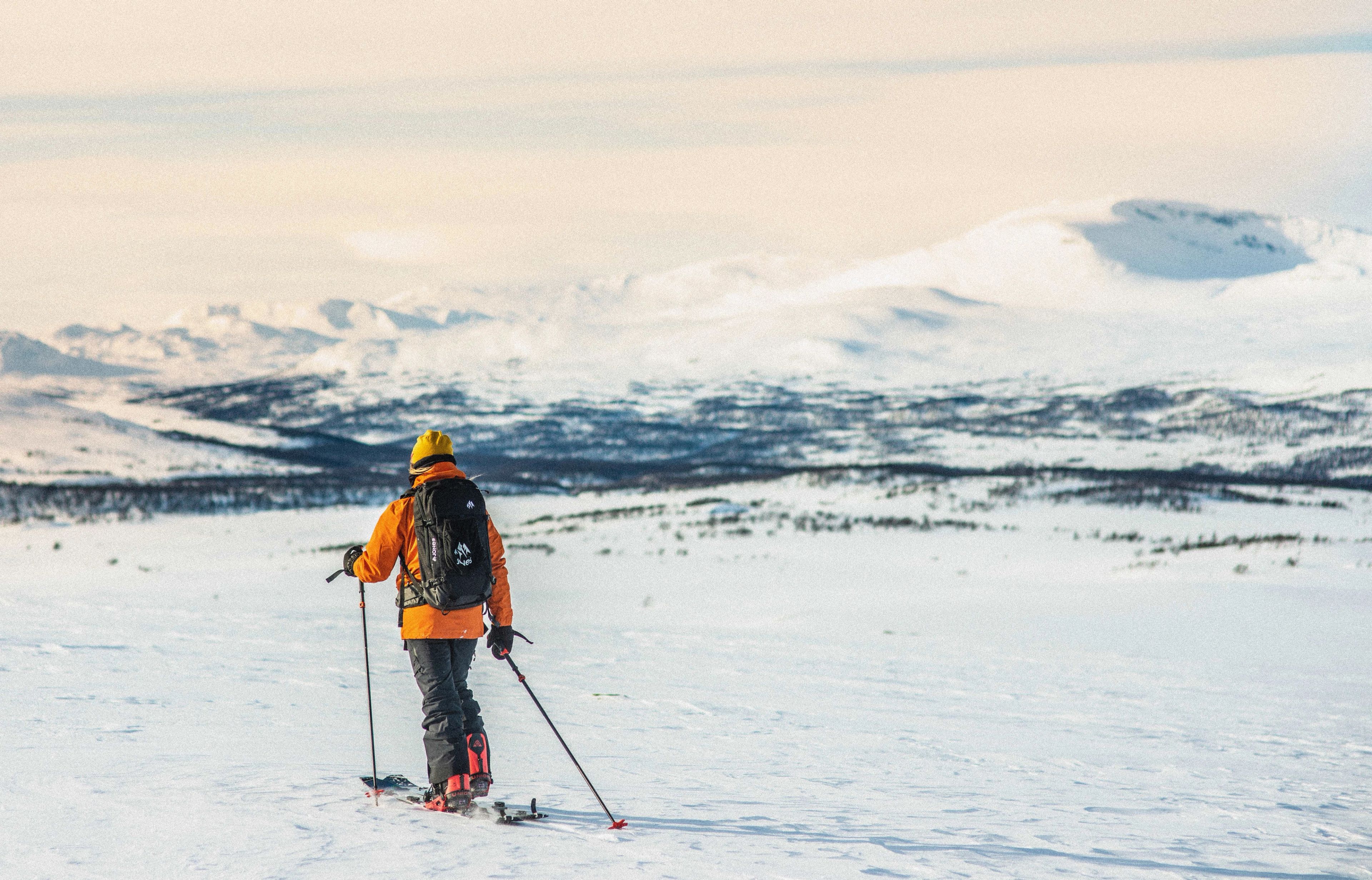 A woman ski touring on alpine touring skis between the mountains.