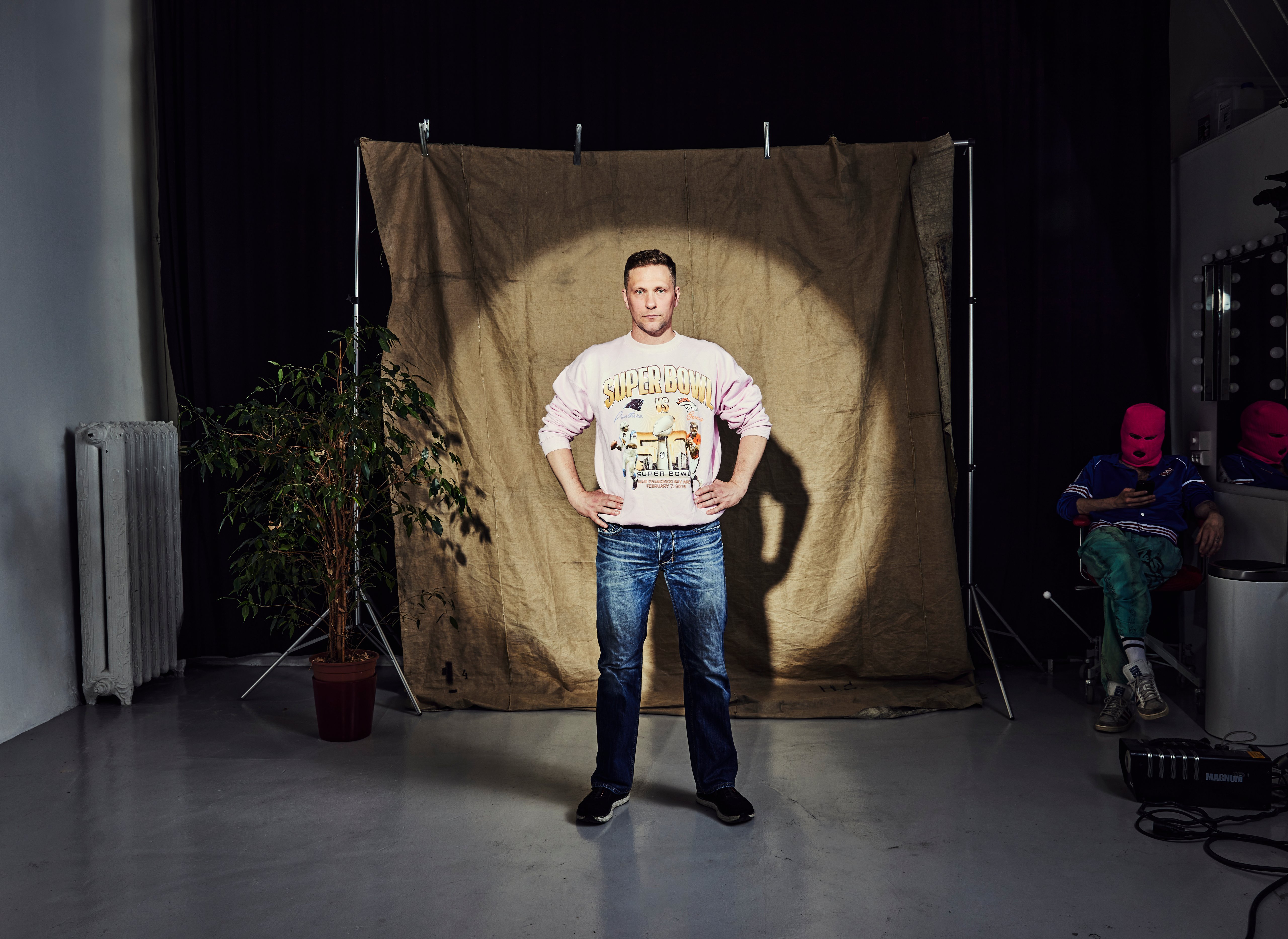 Komikern Magnus Betnér står framför en bakgrund med händerna på höfterna.