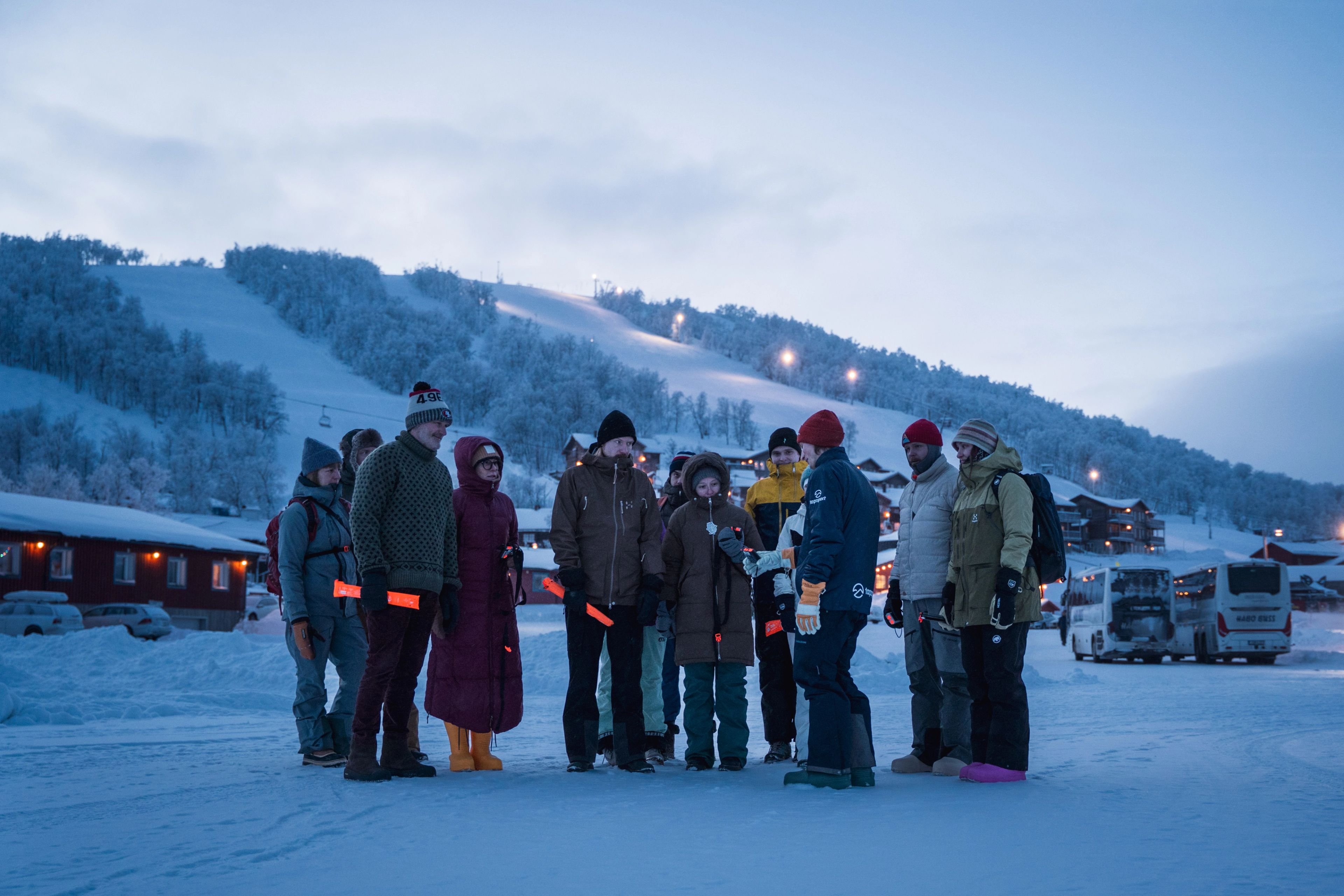 En grupp människor som lyssnar på en instruktör i snön.