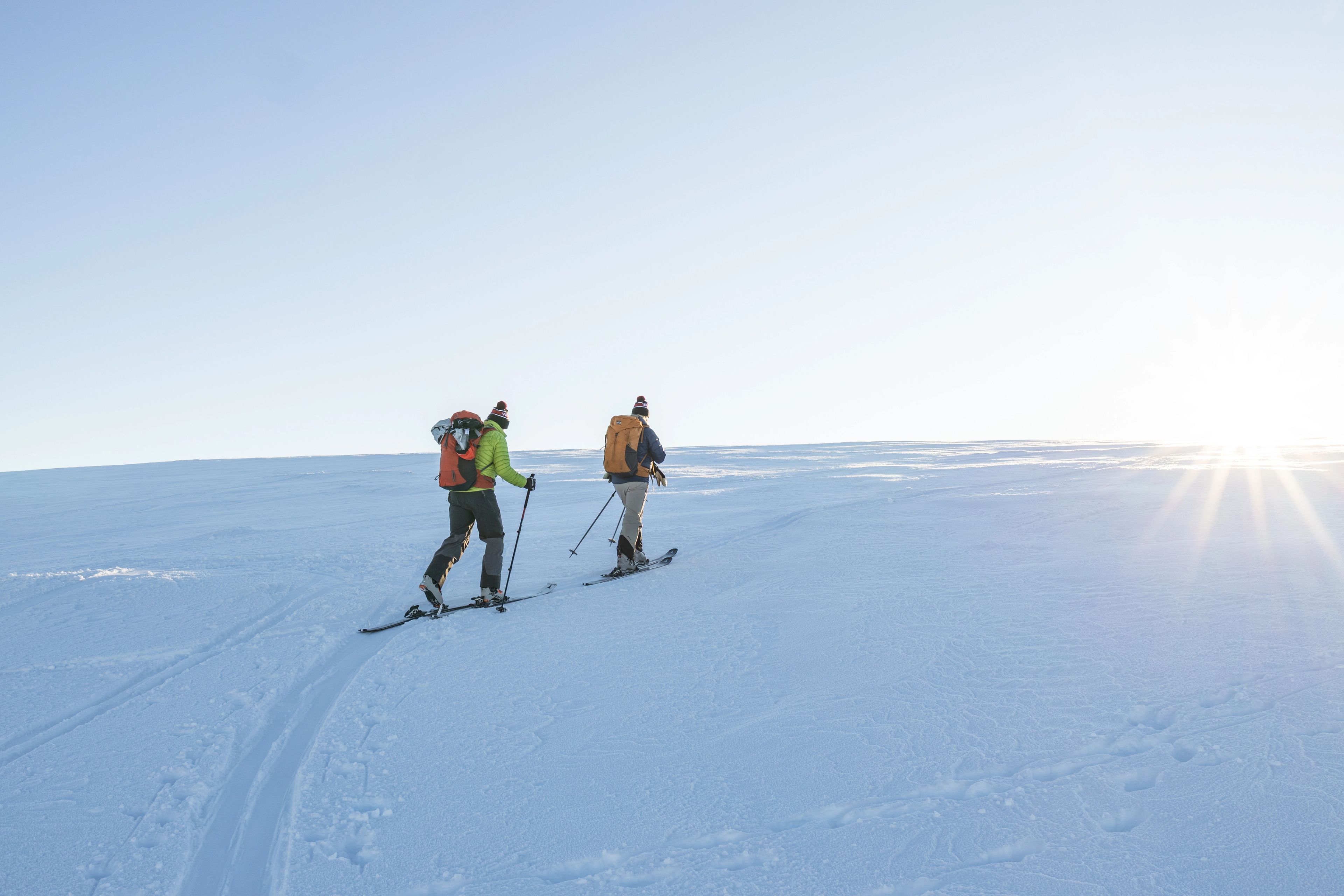 Några personer som går upp med skidor för ett snötäckt fjäll.