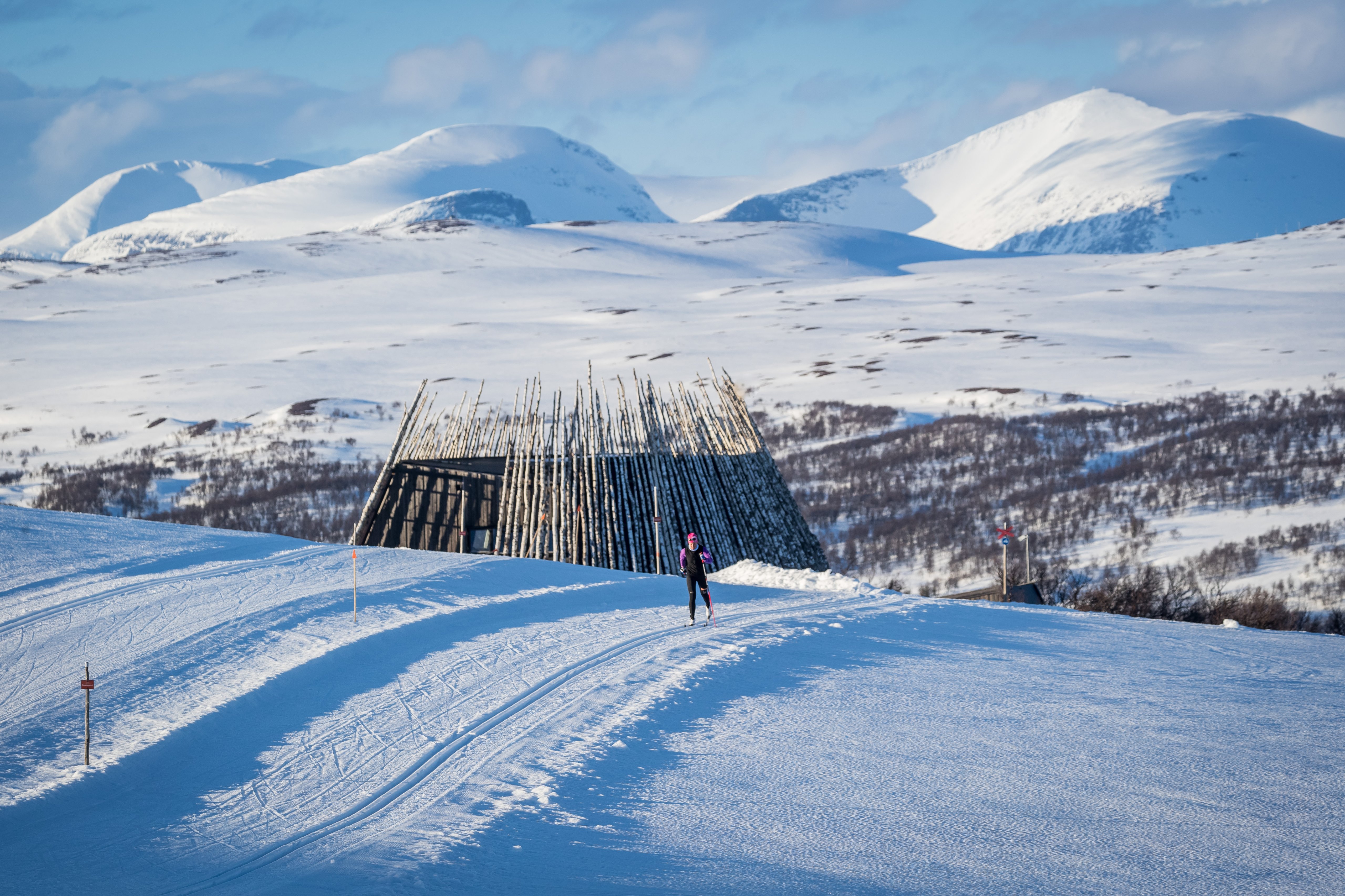 En person som åker längdskidor på toppen av en ett snötäckt fjäll.