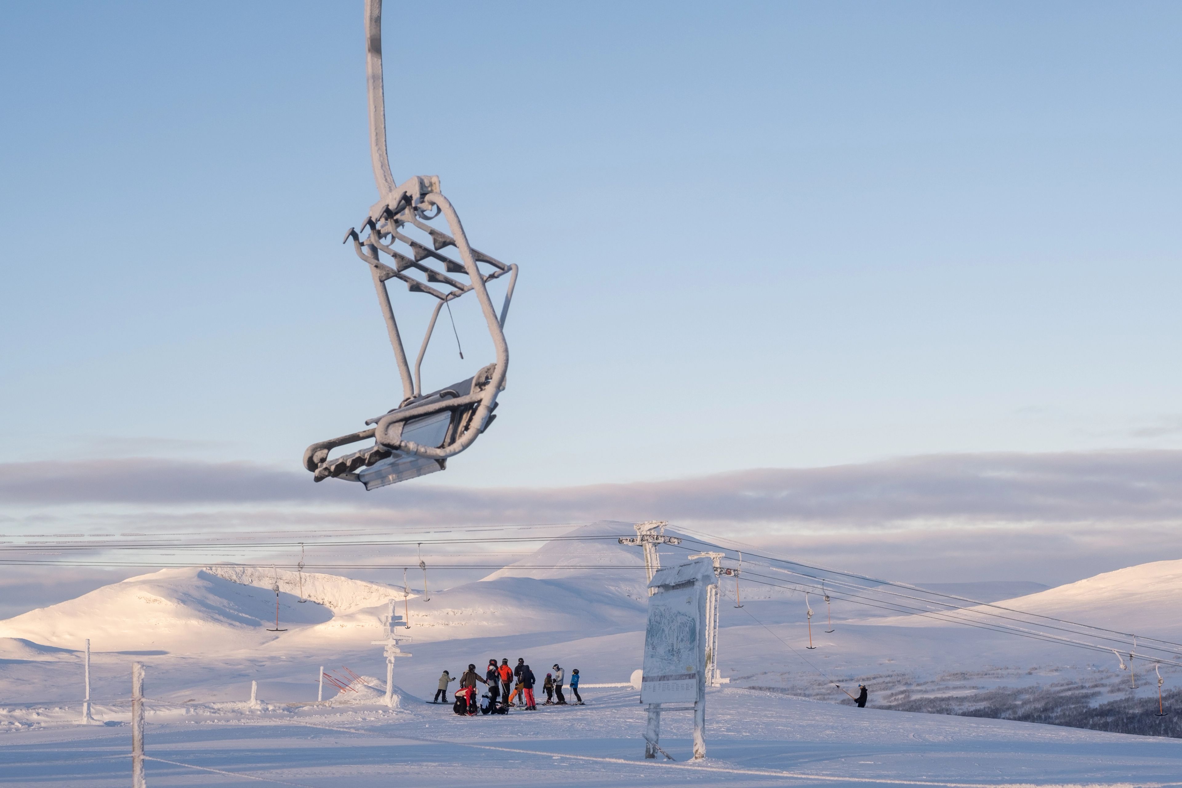 Skidlift ovan en grupp skidåkare på ett snötäckt fjäll.