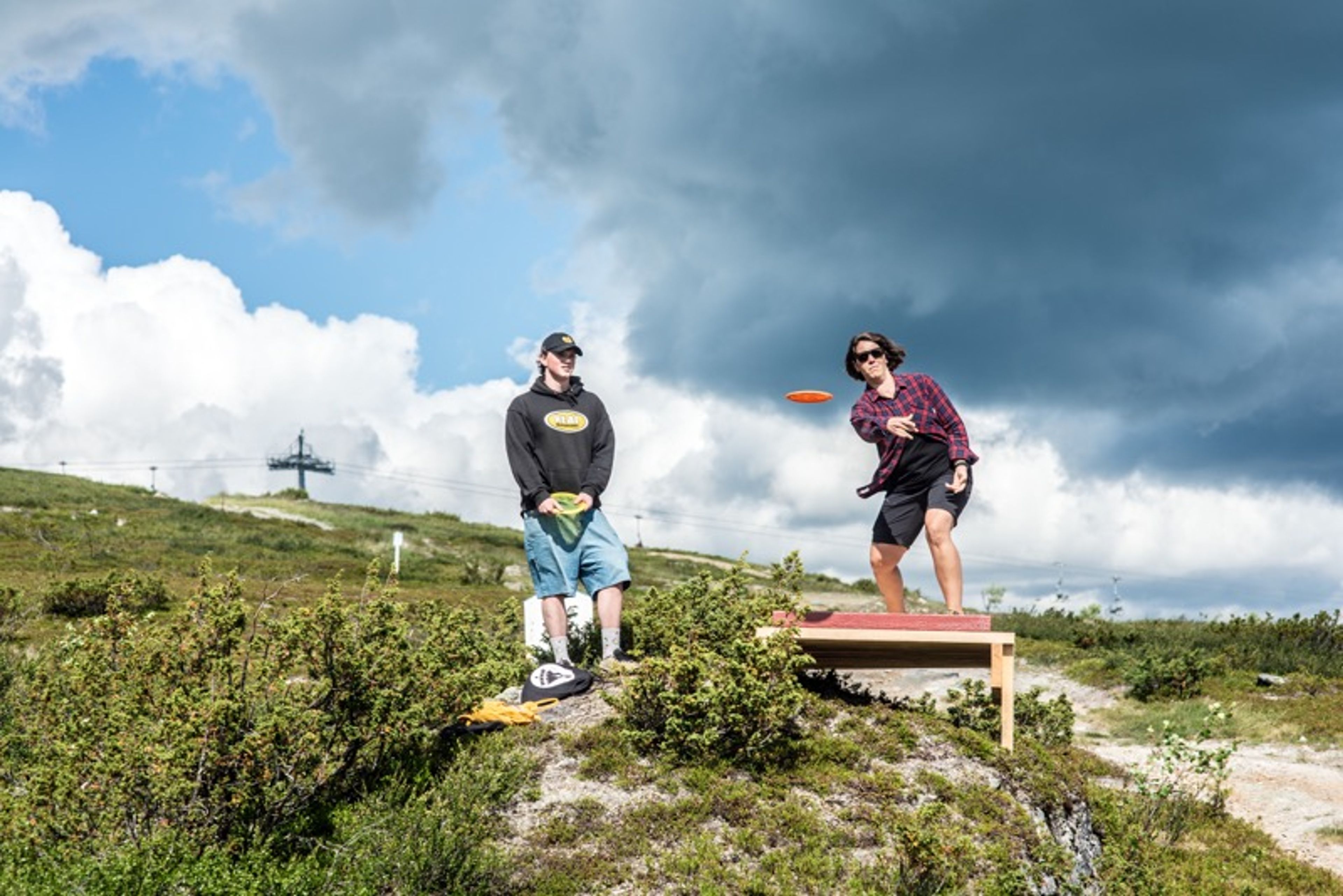 En man och en kvinna som spelar discgolf på ett fjäll.