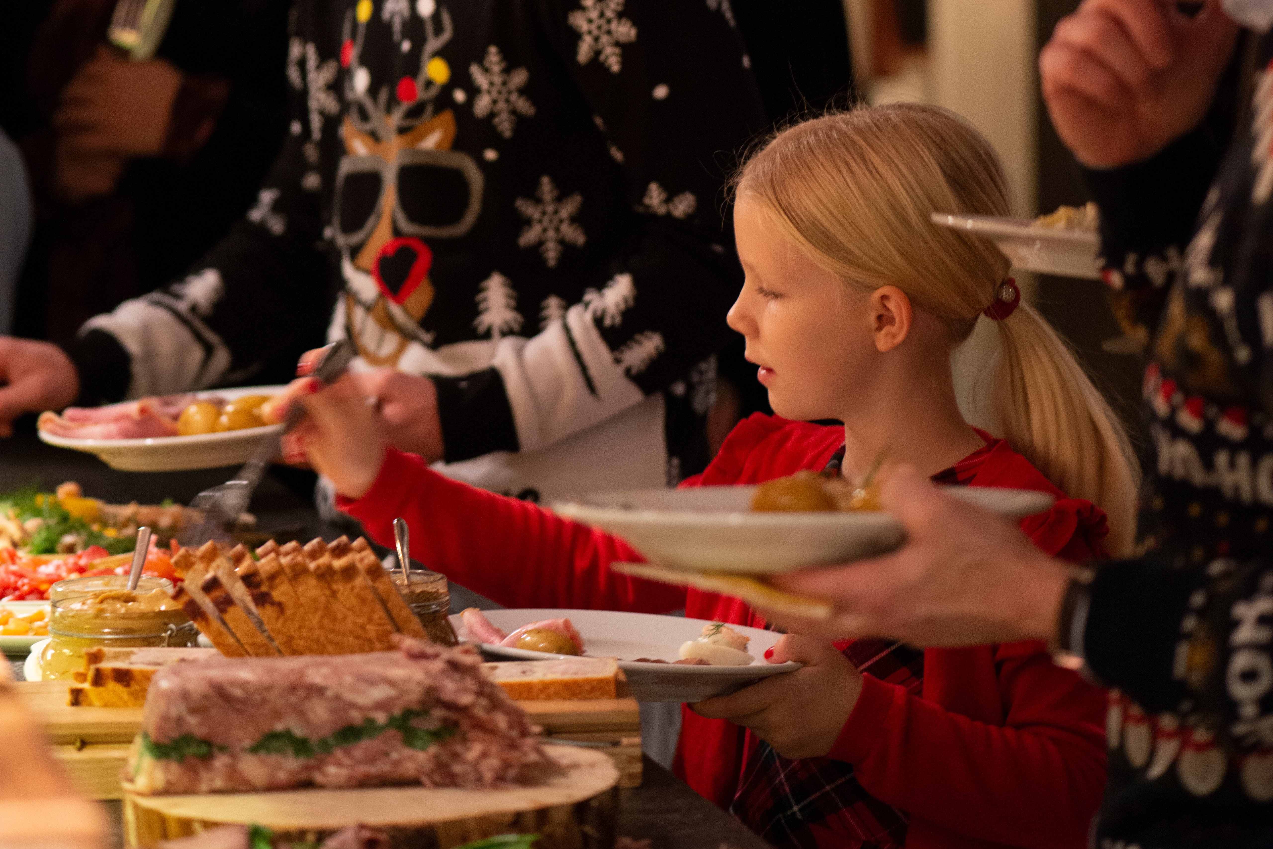 En grupp människor som står runt ett julbord med tallrikar med mat.