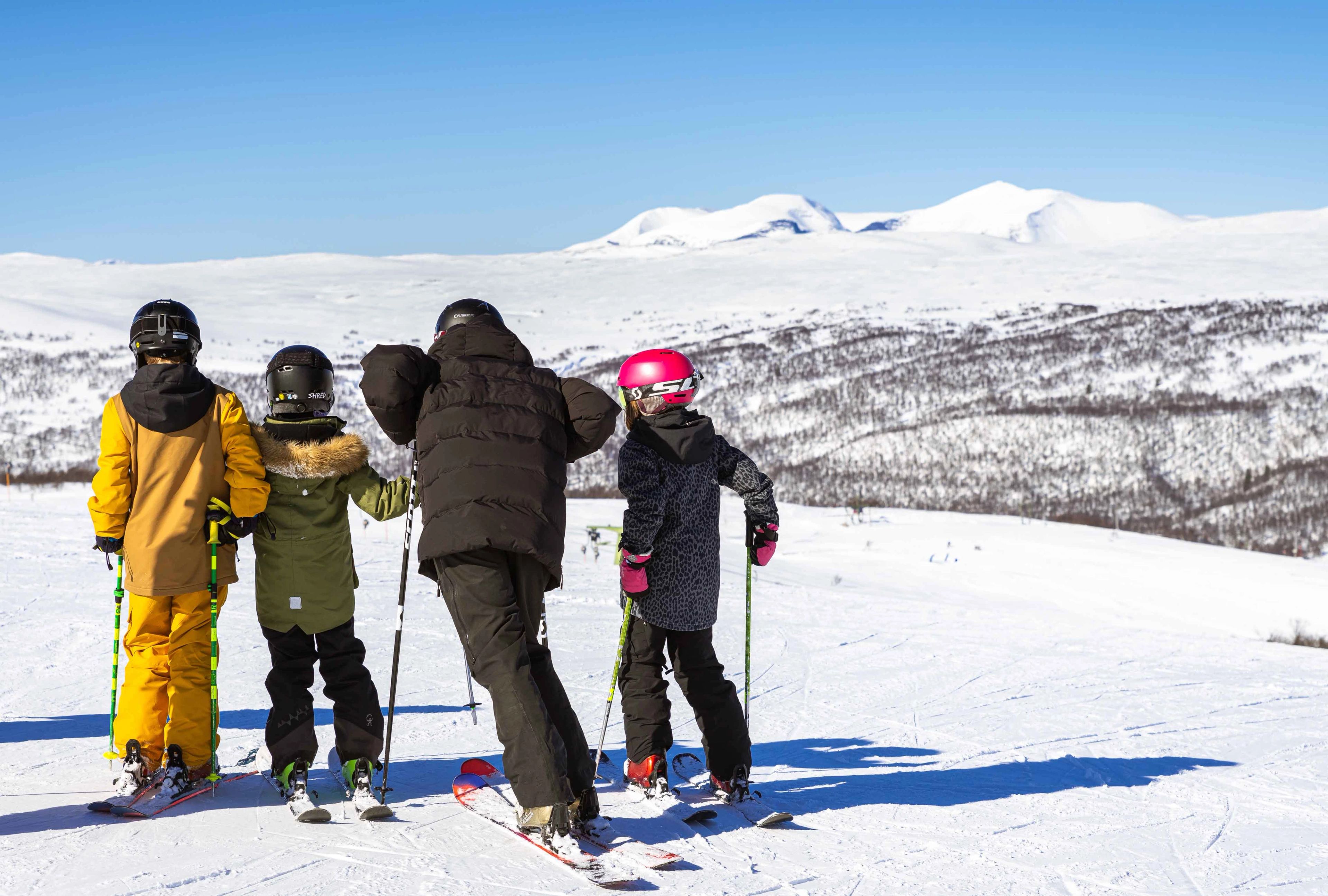 En grupp människor som åker skidor på toppen av en snötäckt sluttning.