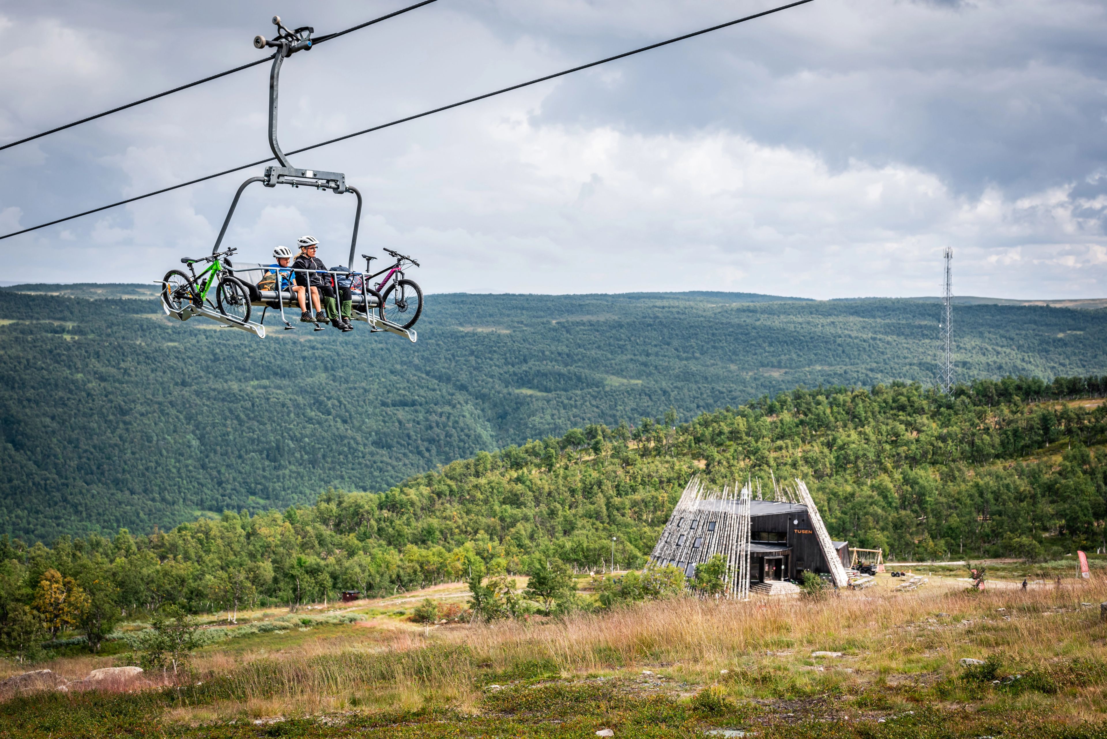 Två cyklister som åker lift över en cykelpark