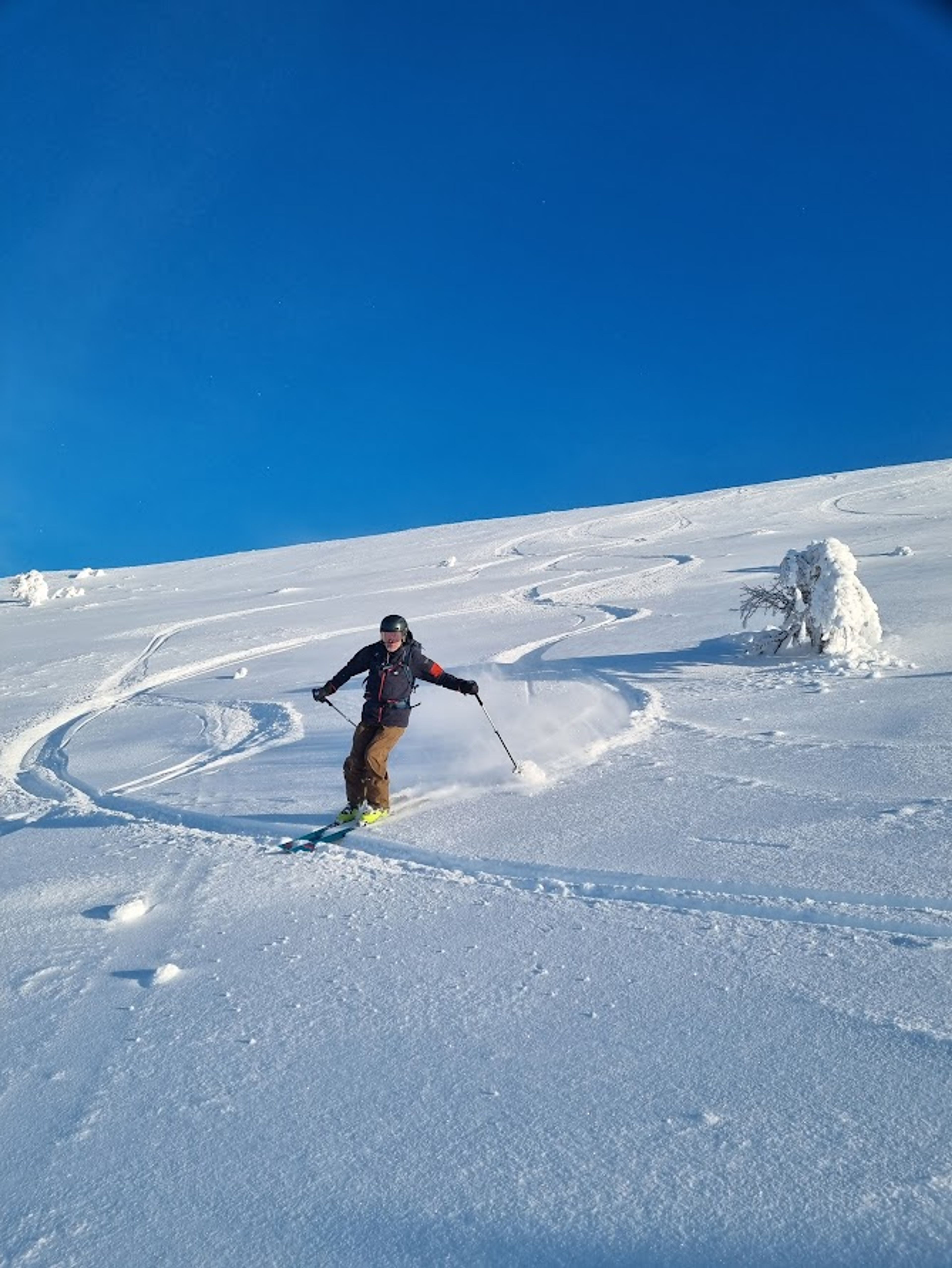 En man som åker skidor nedför en snötäckt sluttning.