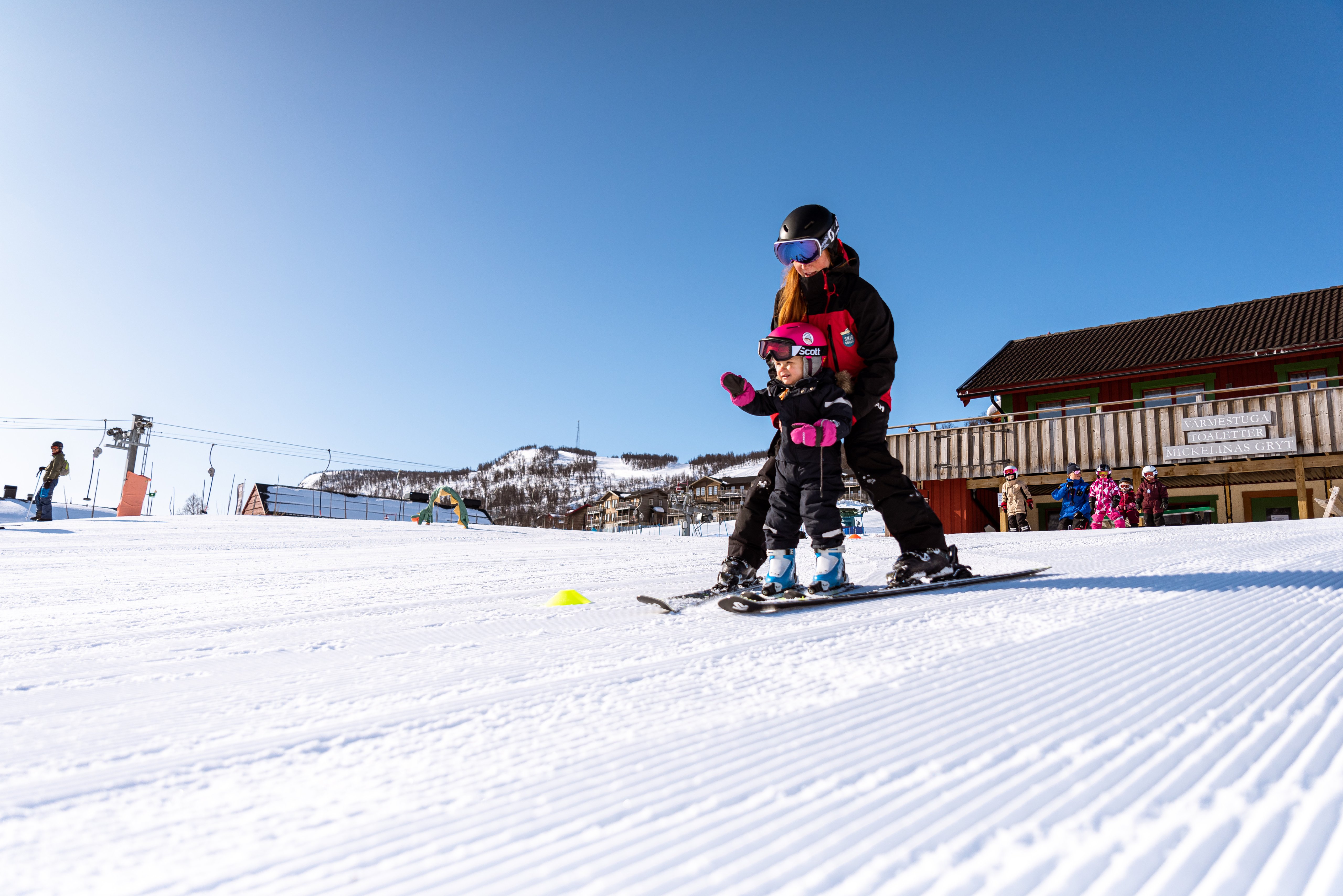 A ski instructor teaching a child to ski down a slope.