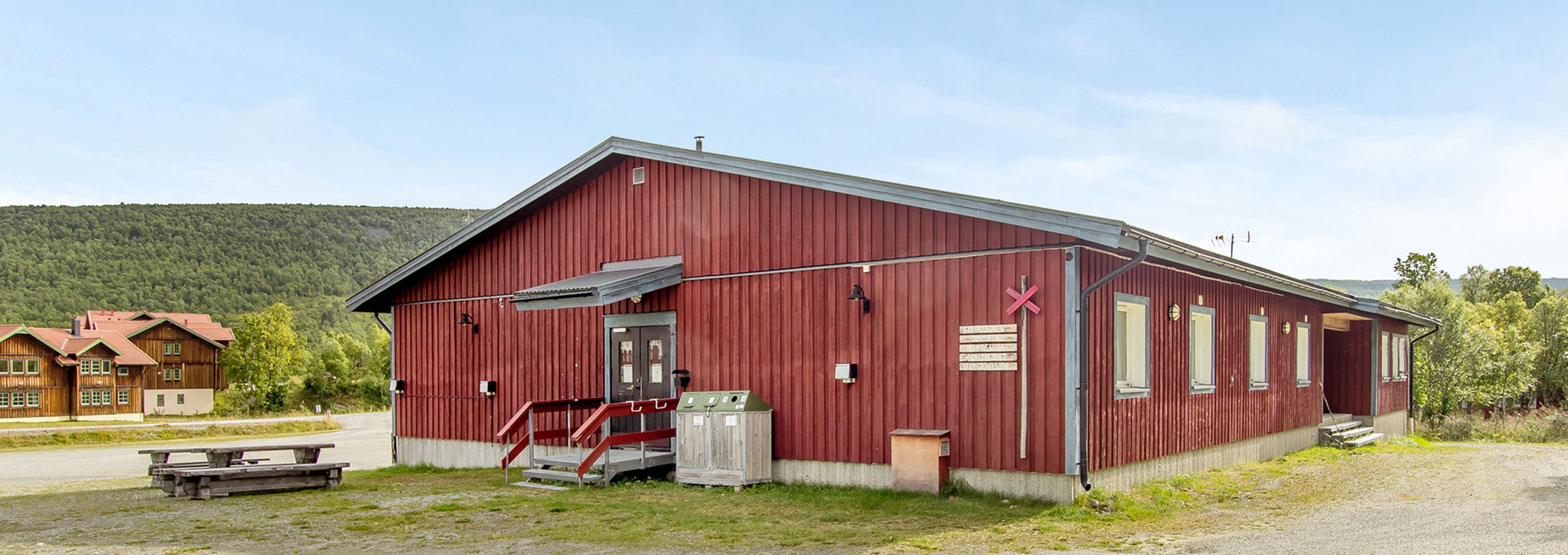En röd byggnad med en bänk framför sig.
