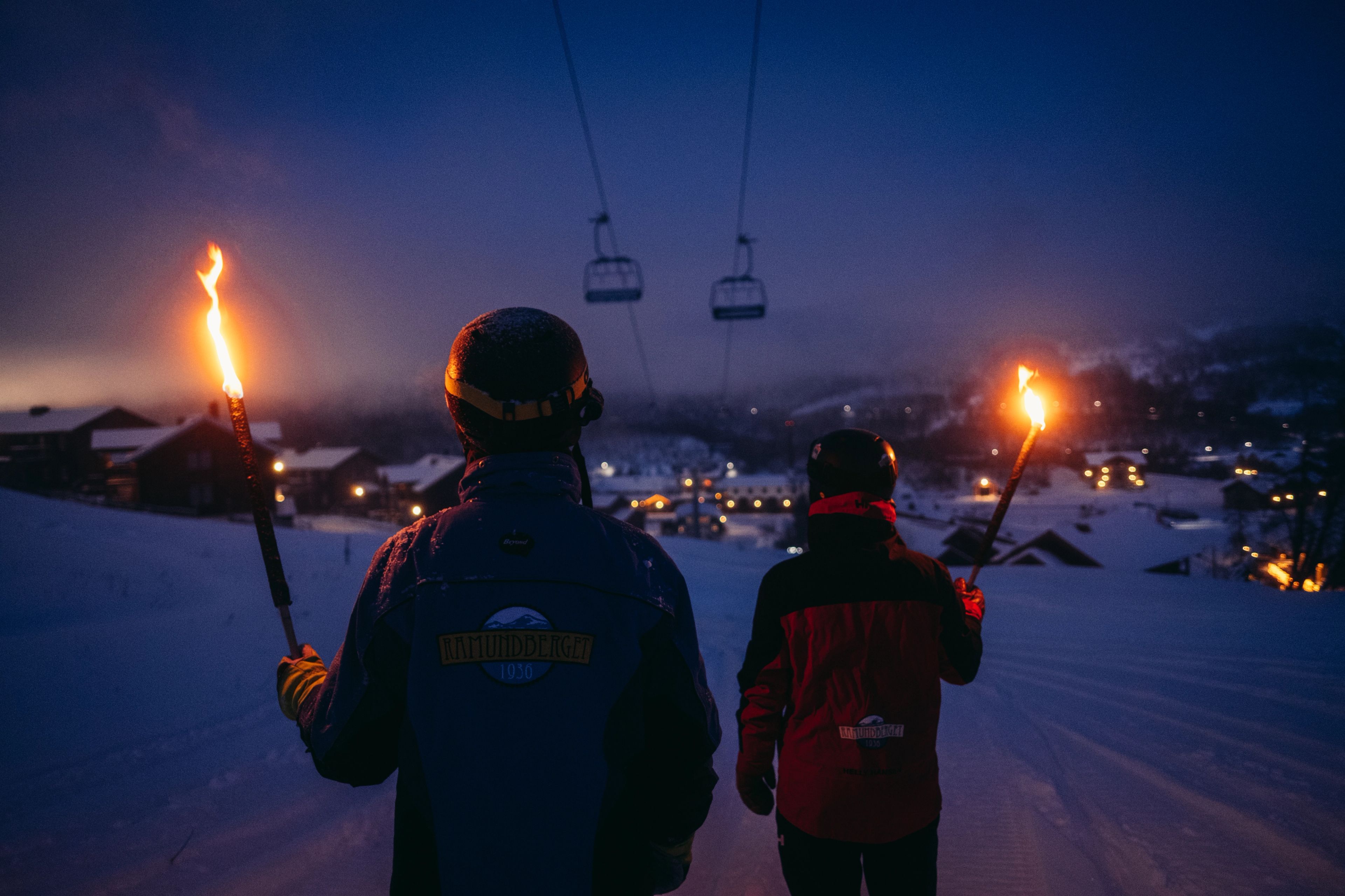 Några personer som står i snön med facklor.