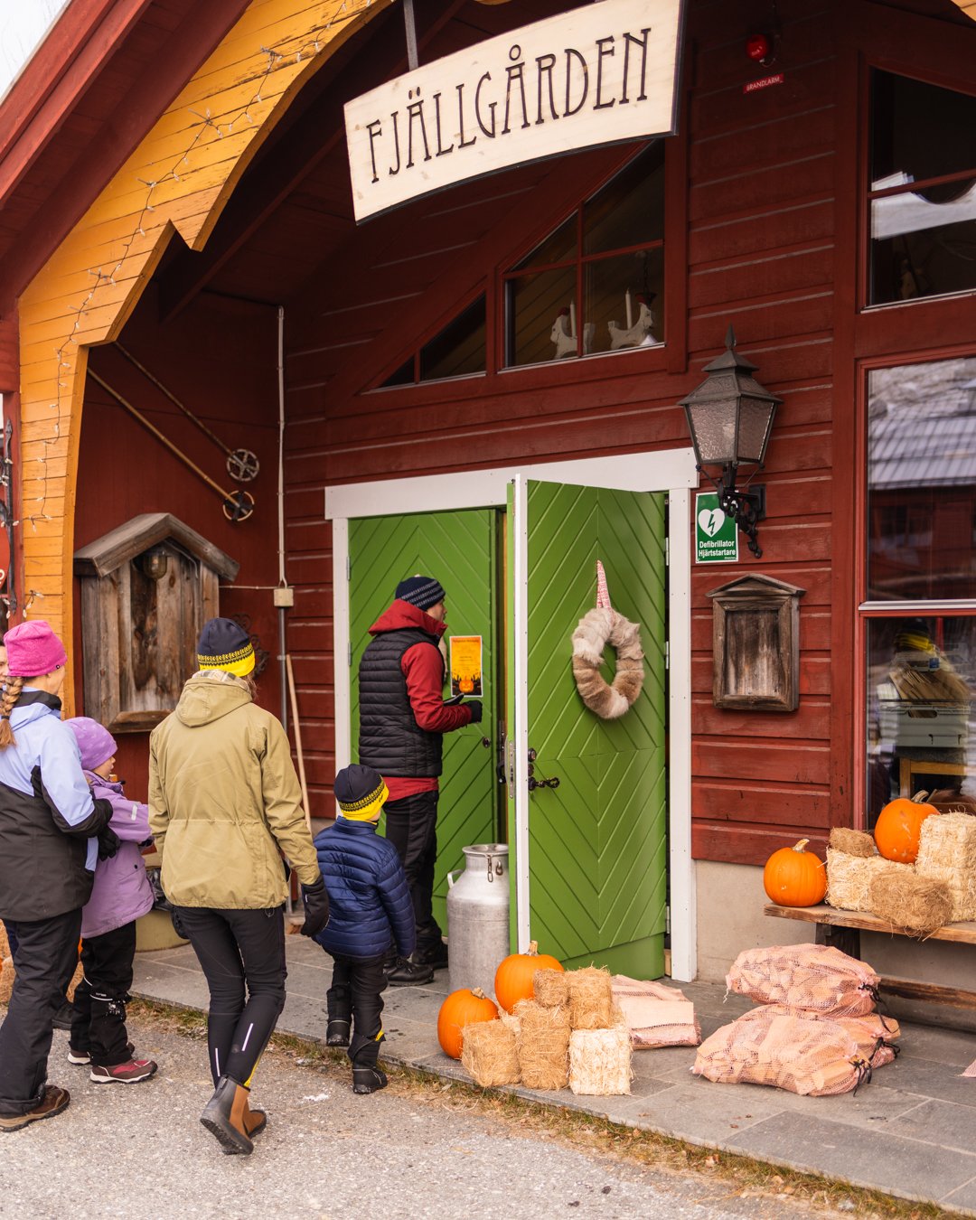 En grupp människor som står utanför Ramundbergets Fjällgård som är pyntat med pumpor och höbalar.