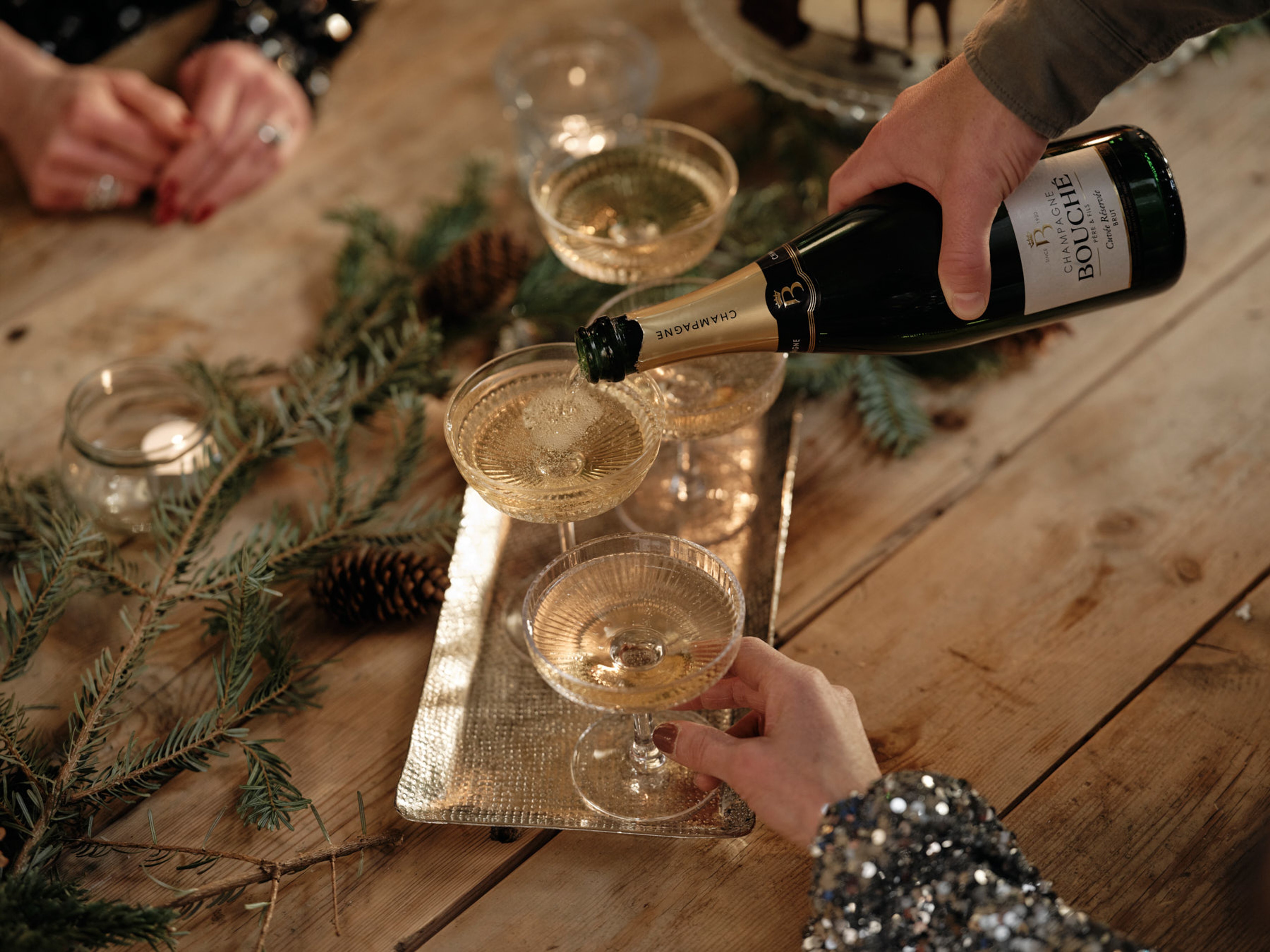 En person som häller upp ett glas mousserande vin i ett vinglas.