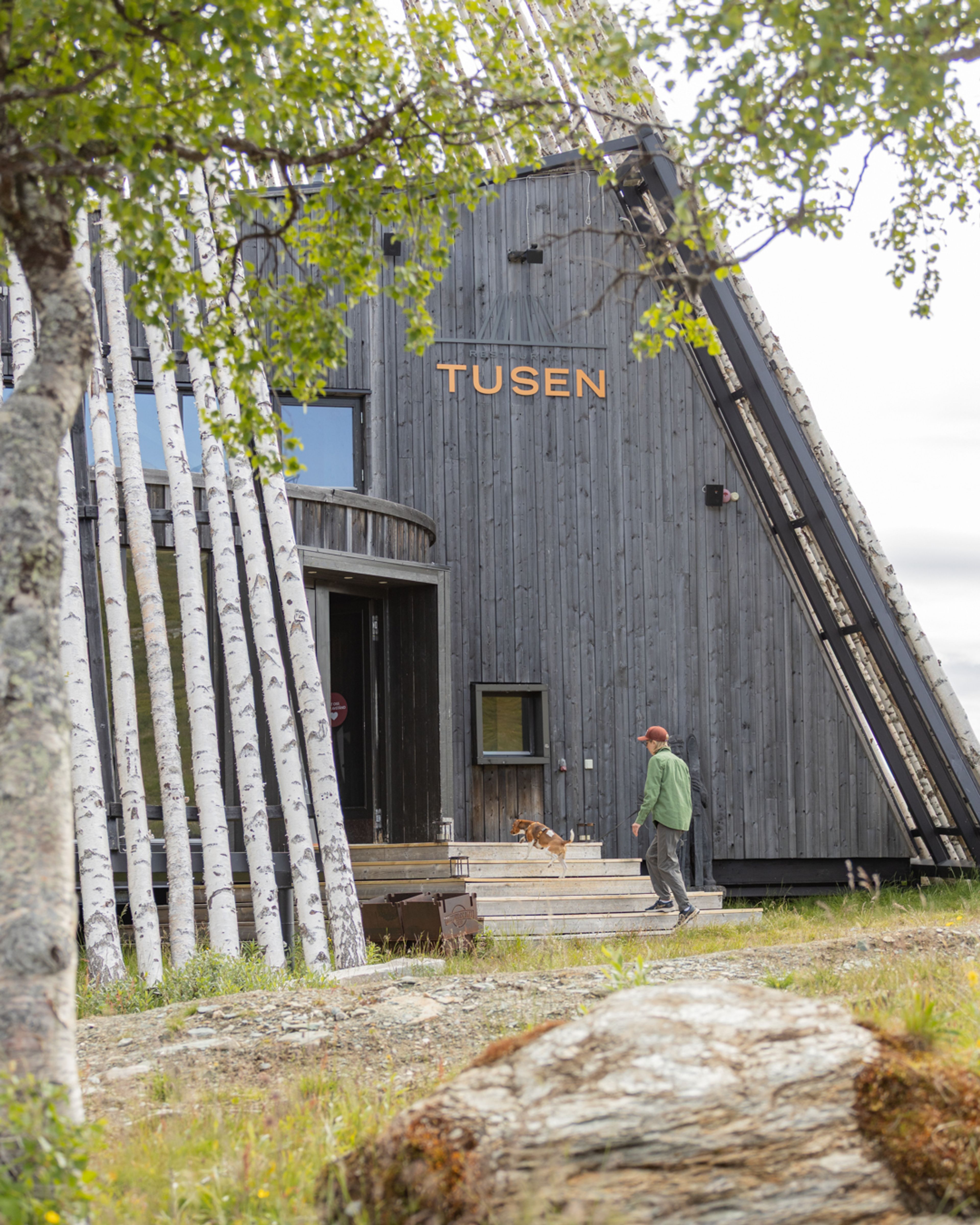 En kvinna som går uppför en trappa till en träbyggnad.