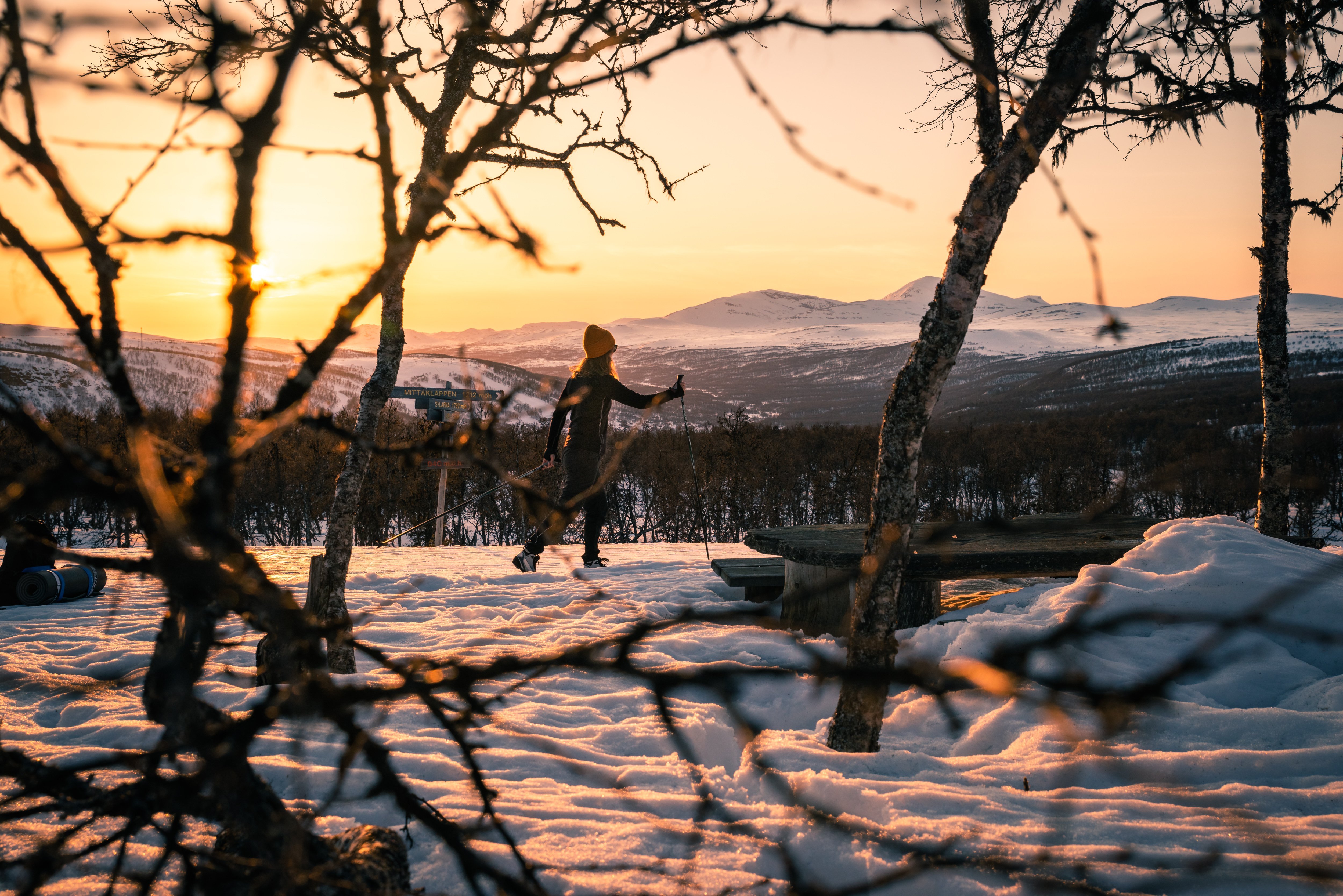 En person som åker längdskidor i solnedgången med fjällen i bakgrunden.