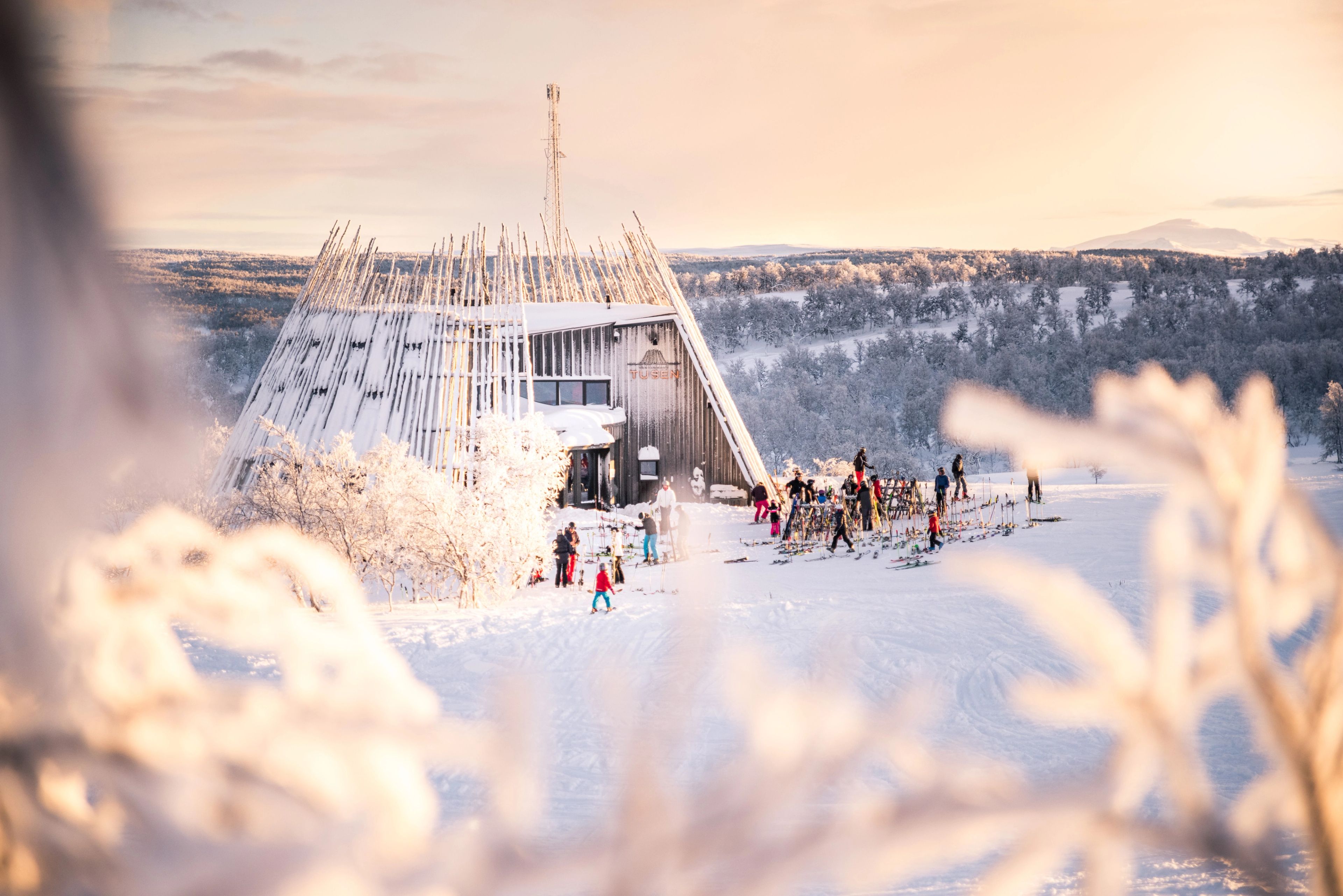 En grupp människor på skidor som står utanför en snöklädd toppstuga.