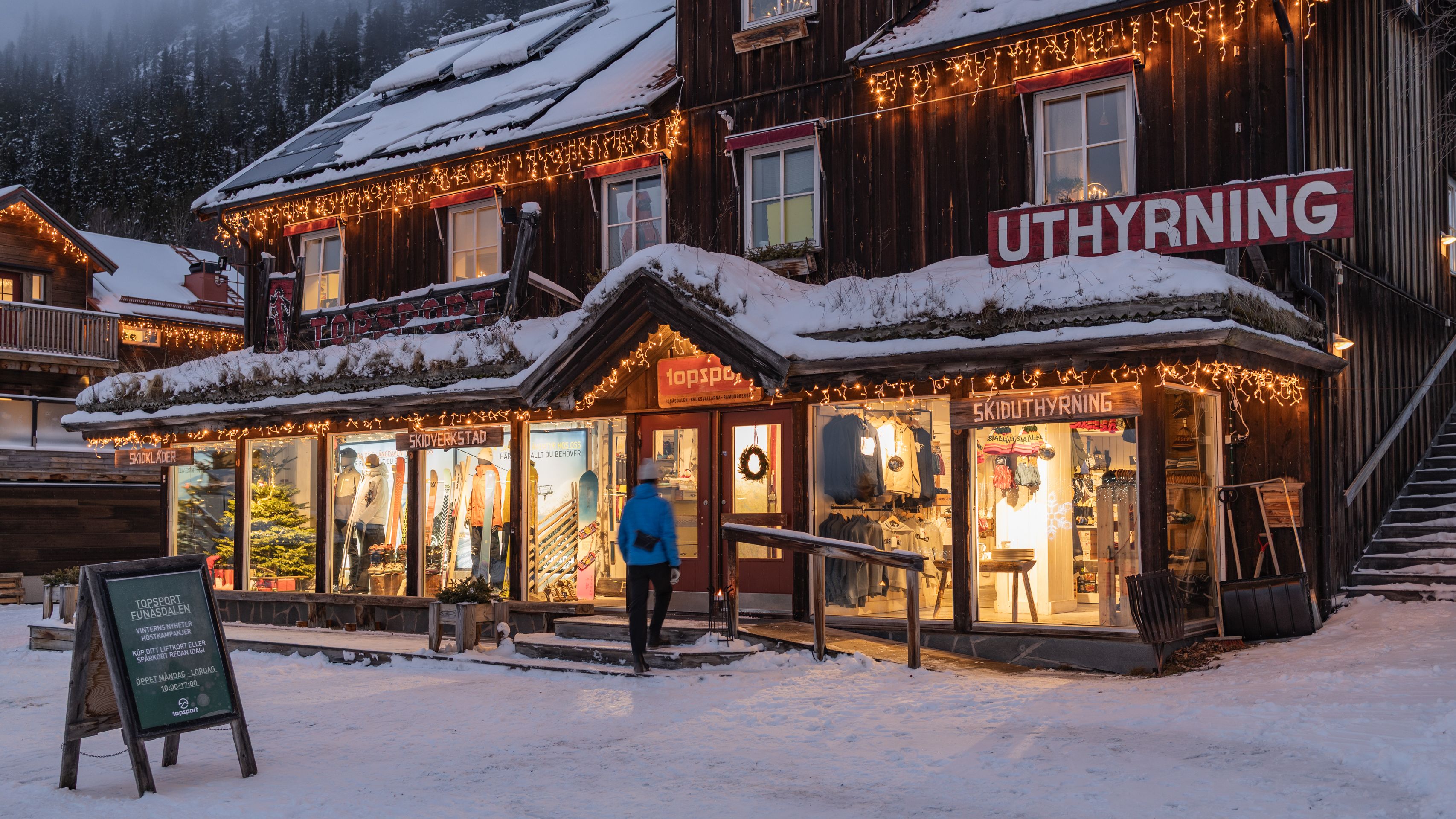 En man som står framför ett skyltfönster utanför en snöklädd sportbutik.