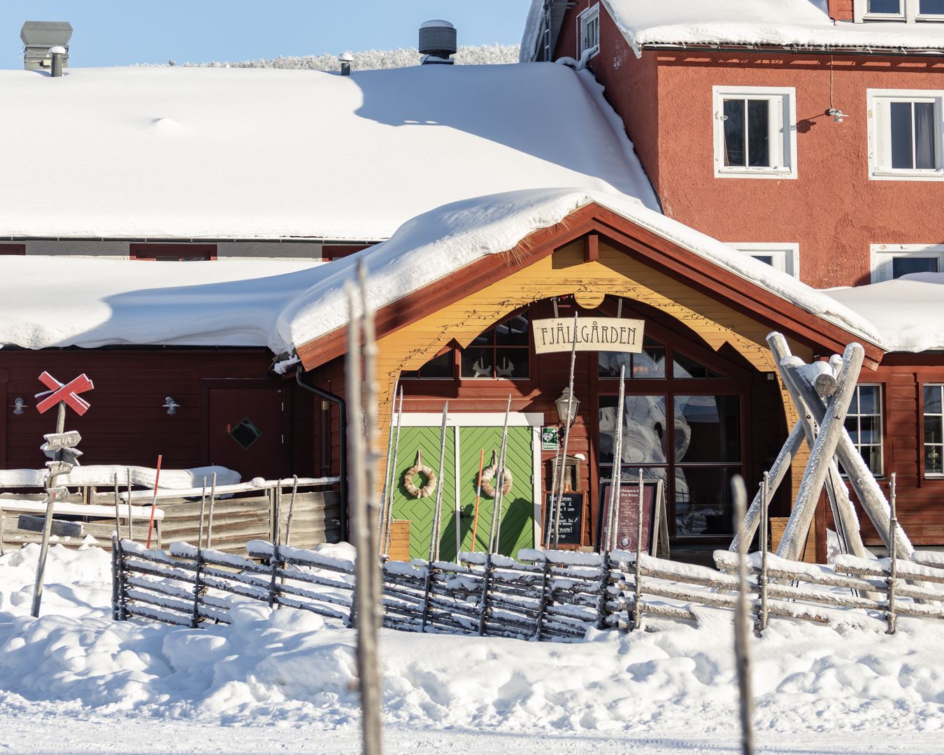 Ett snötäckt fjällhotel intill en gärdesgård.