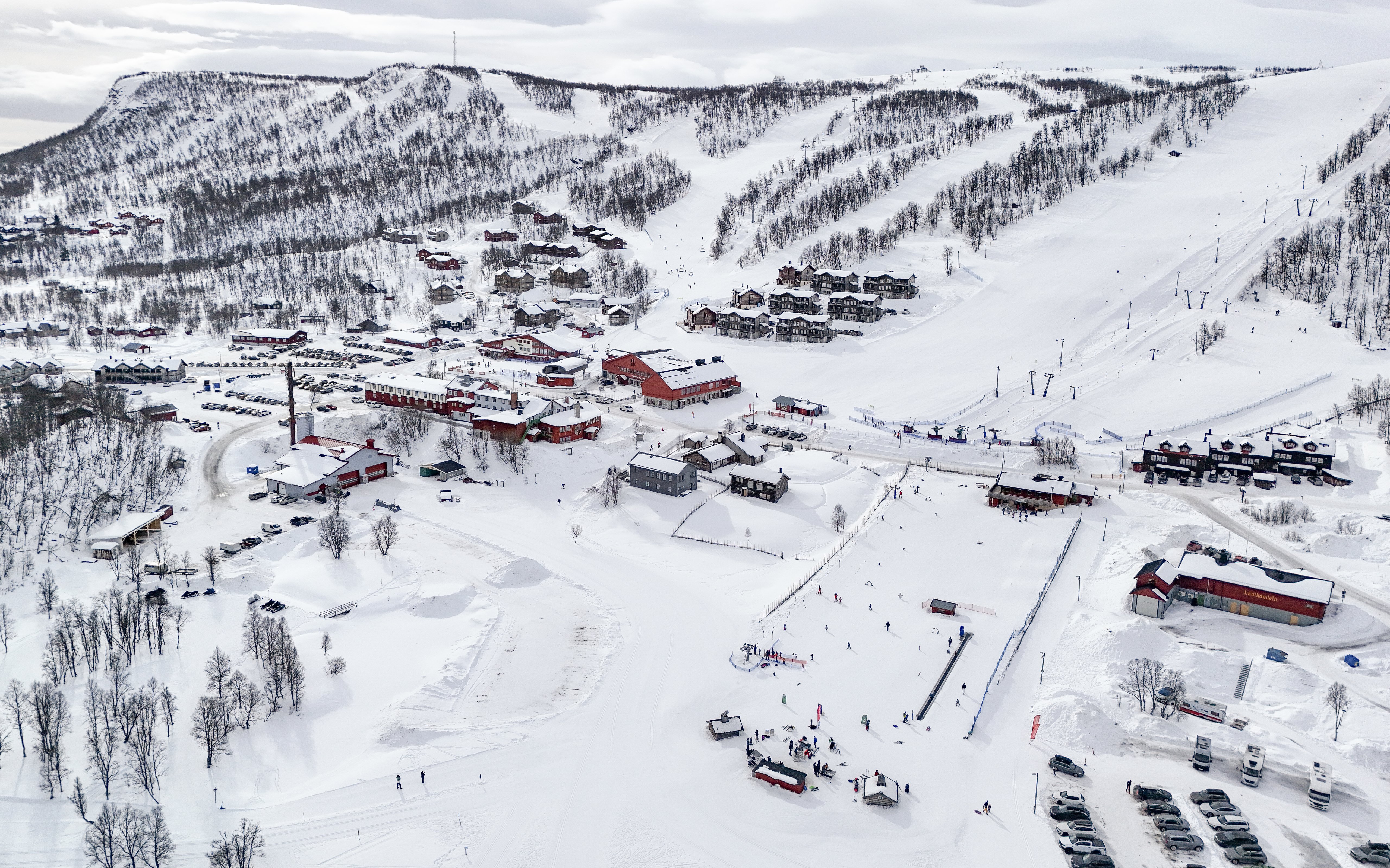 An aerial drone view of a ski resort, with parking and motorhome pitches in the valley below.