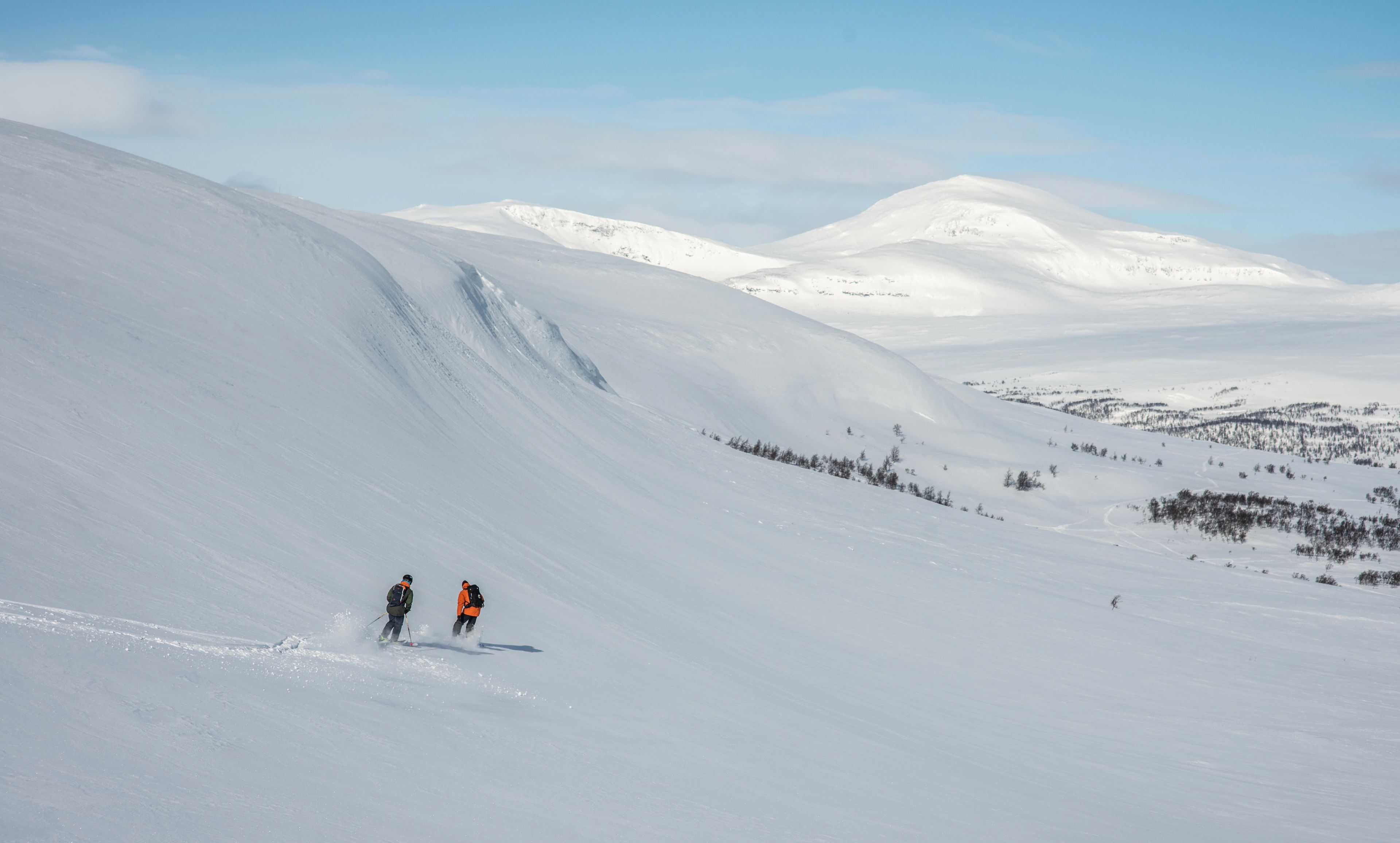 En grupp människor som står på toppen av en snötäckt sluttning.