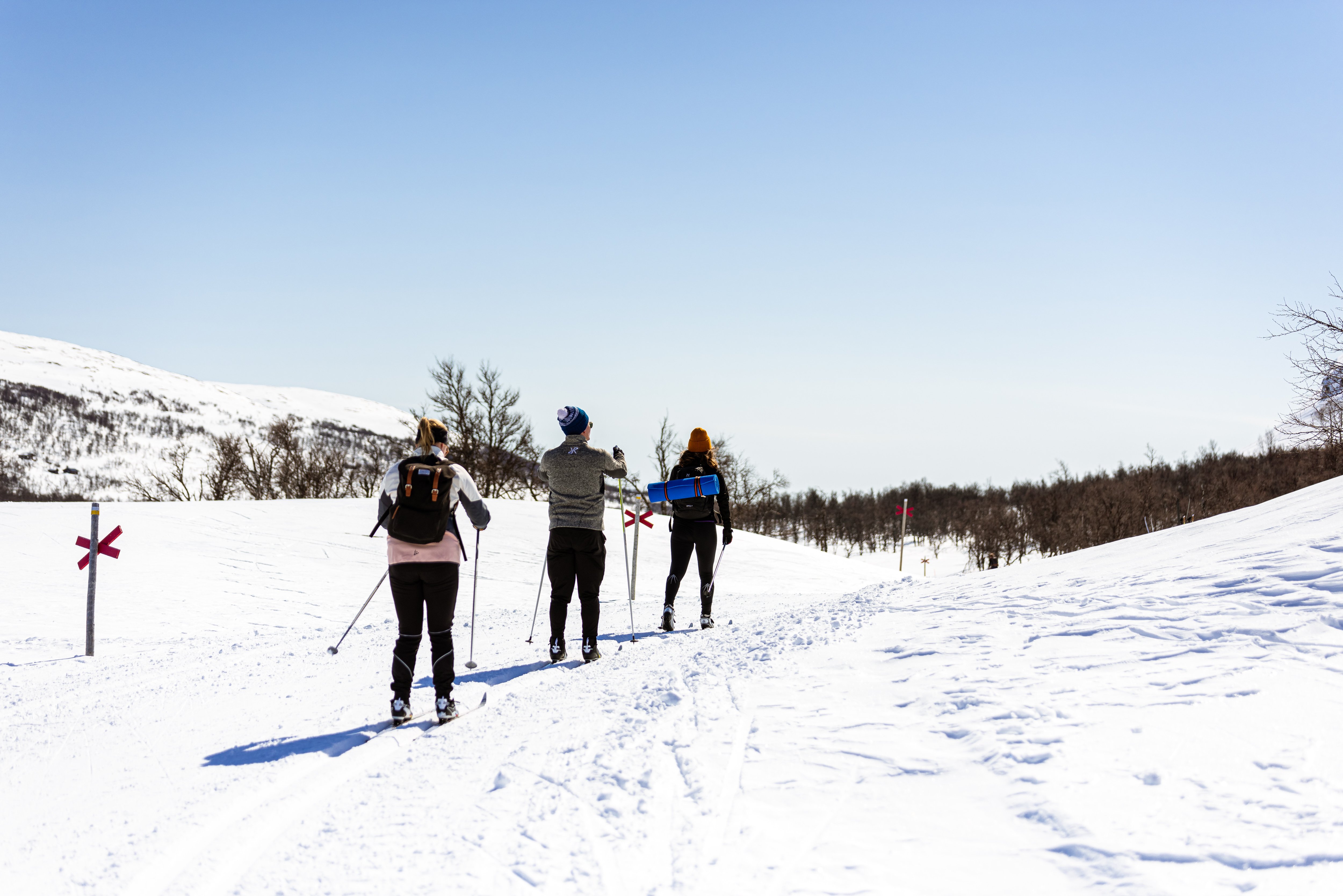En grupp människor som åker längdskidor nedför en snötäckt sluttning.
