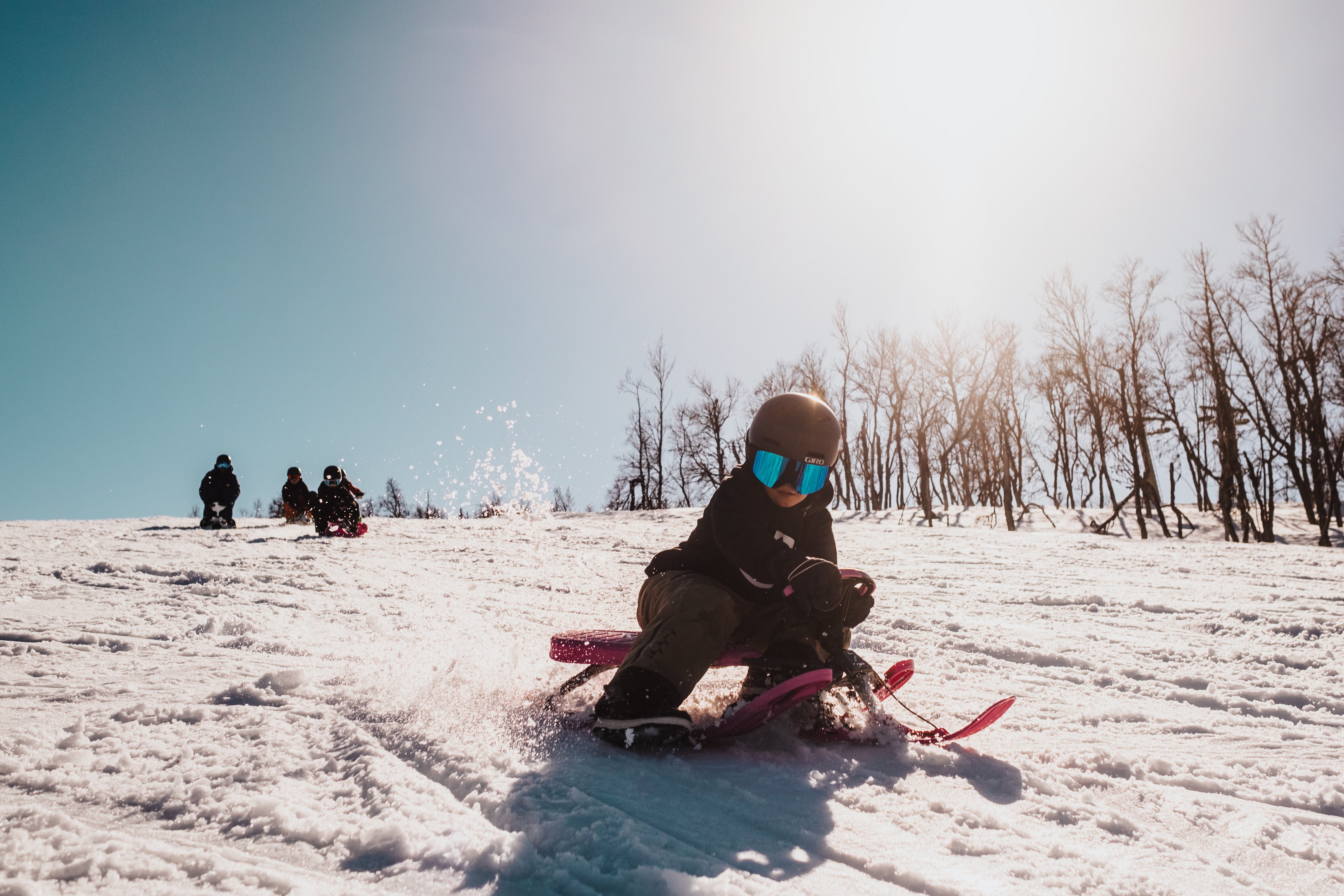 A child riding a snow racer down a snow-covered slope.