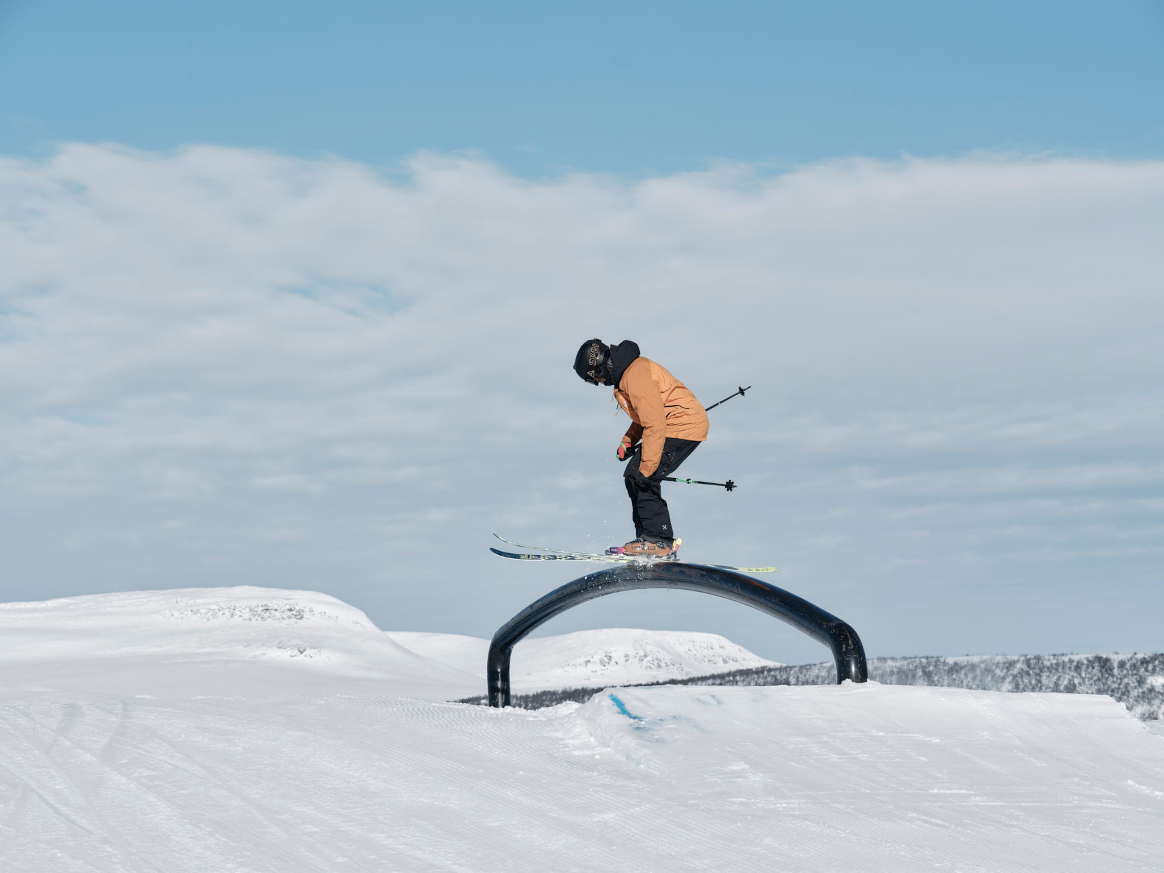 En person på skidor som åker på en rail i snowparken.