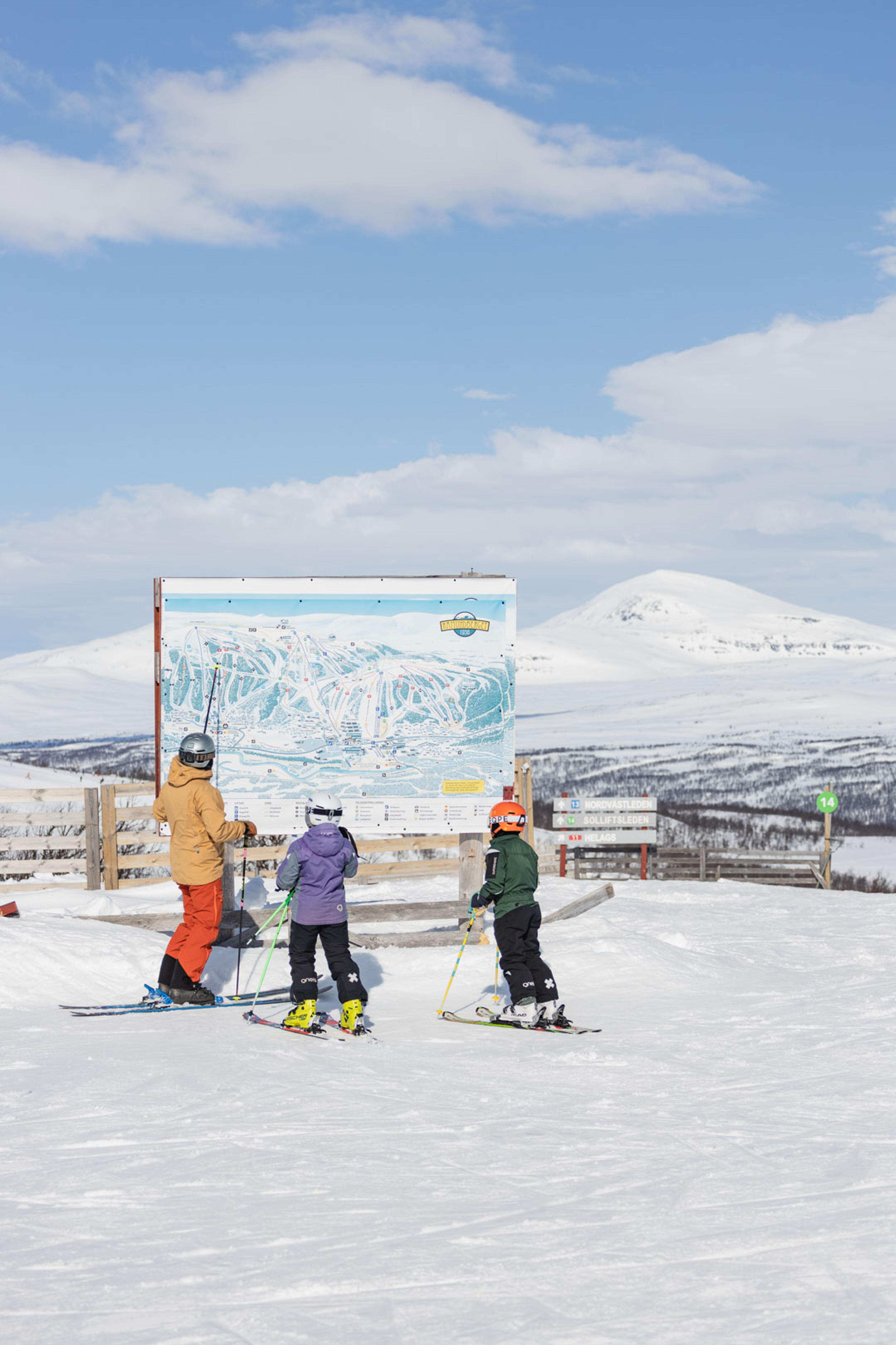En grupp människor som åker skidor på toppen av en snötäckt sluttning.