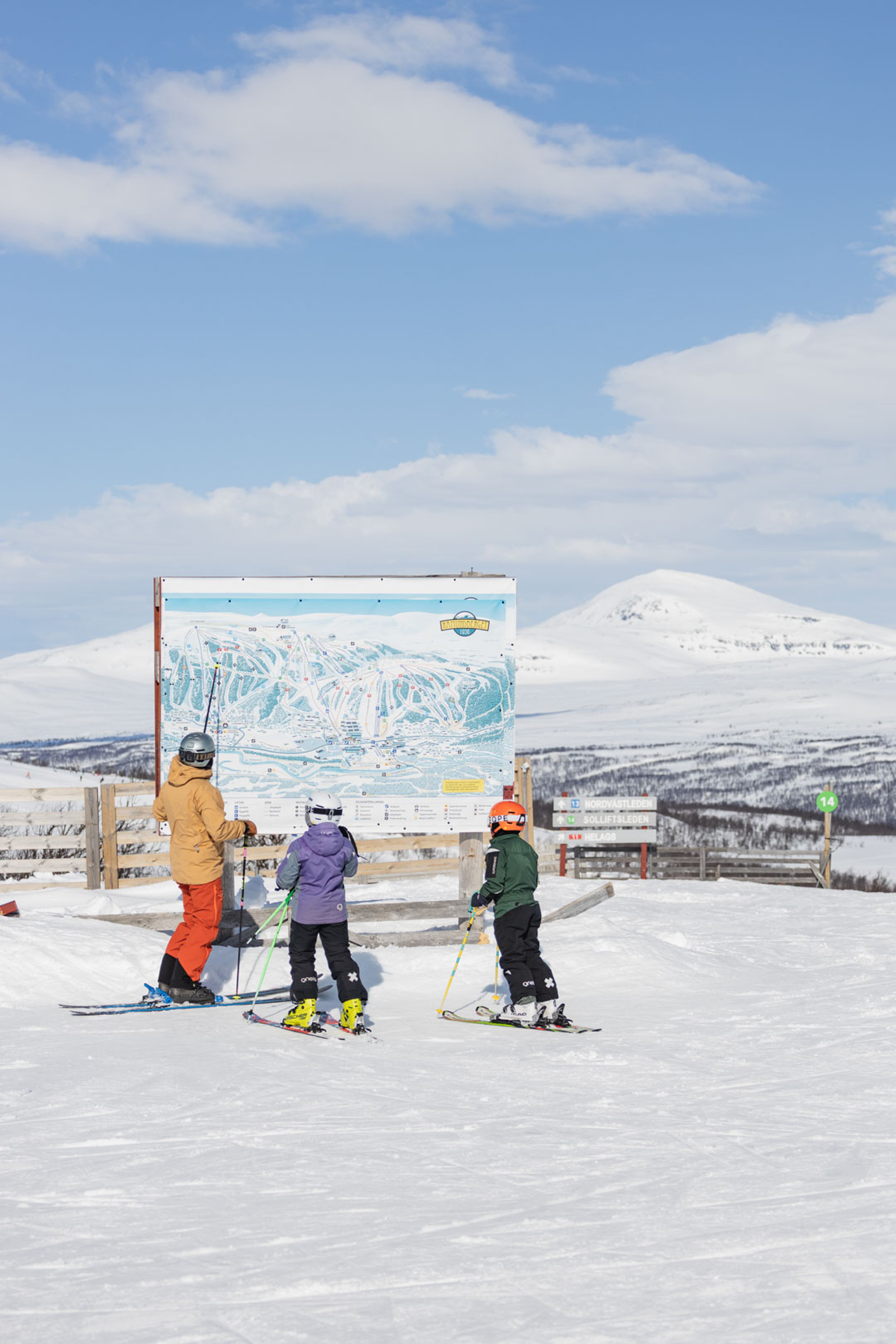 En grupp människor som åker skidor på toppen av en snötäckt sluttning.