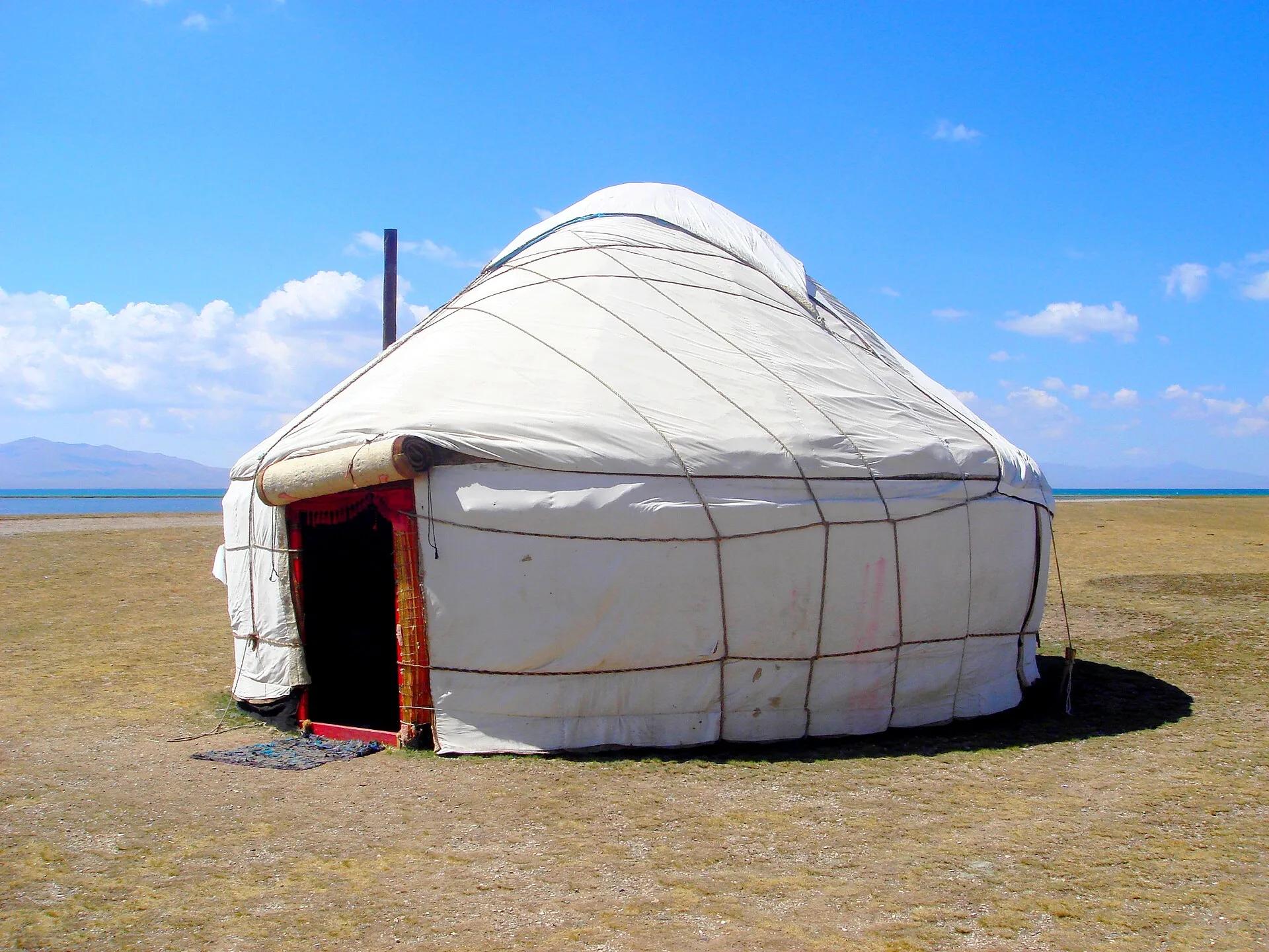 A white yurt standing in open mountain pasture