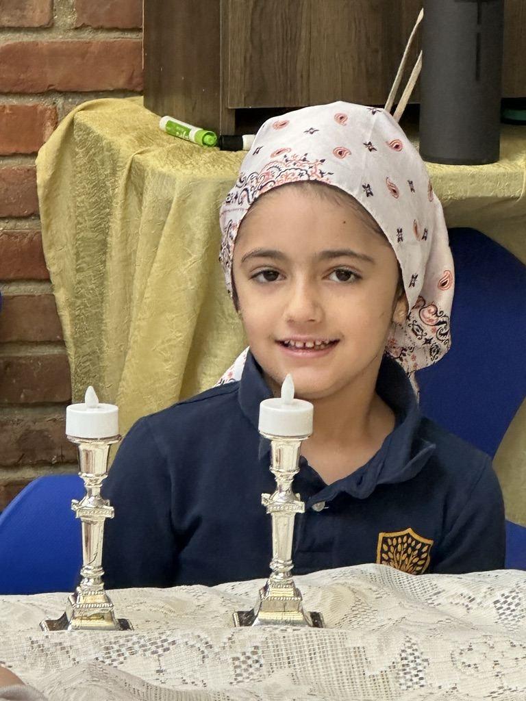 A student with Shabbat candlesticks at the class Shabbat party