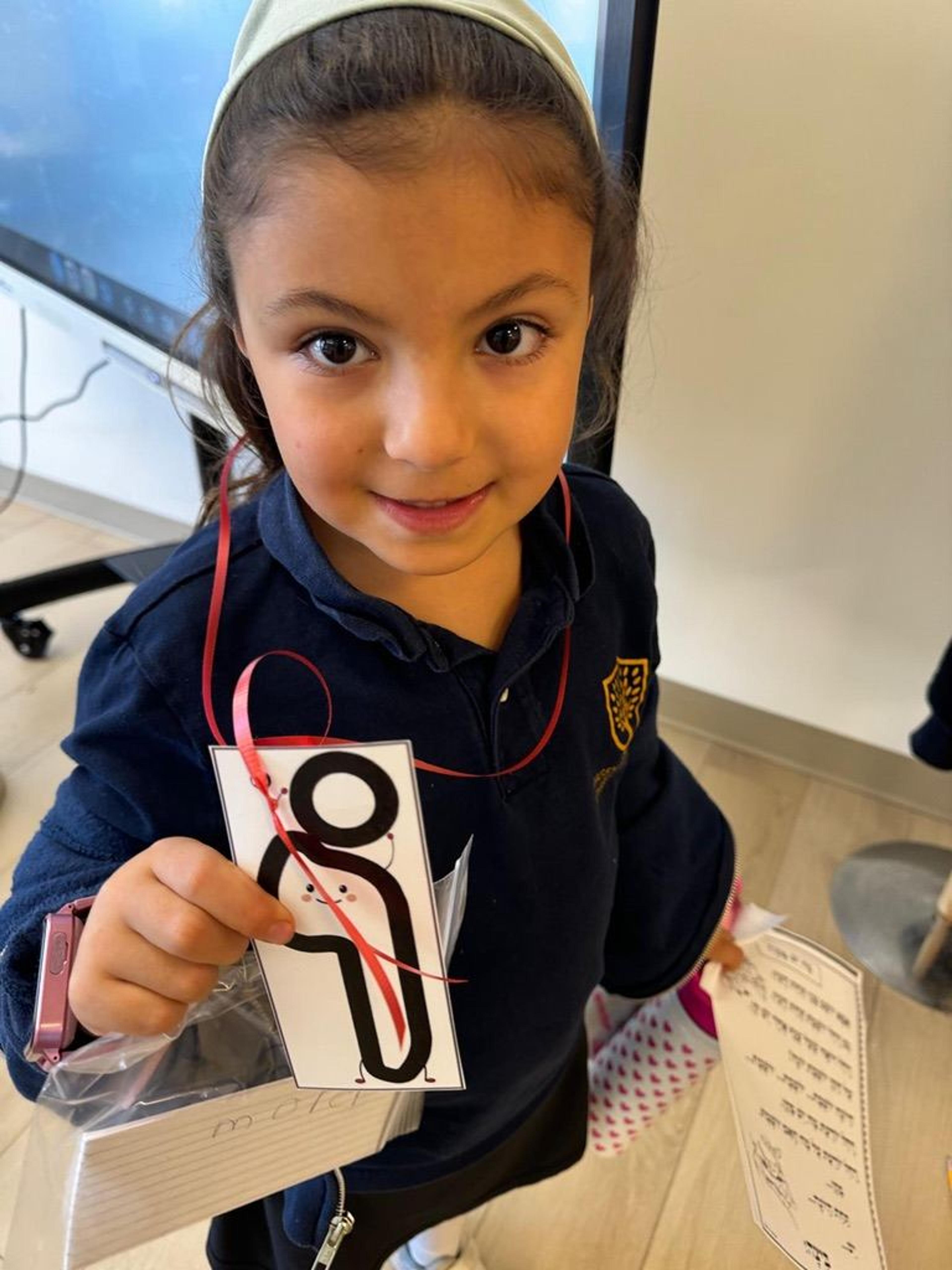 A kindergartener proudly holds up a Hebrew letter card