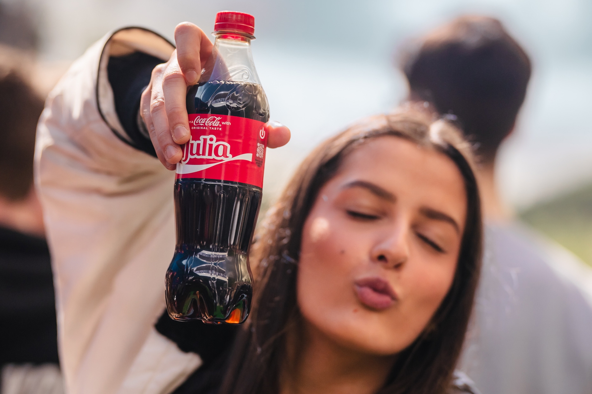 Jente holder opp Coca-Cola flaske og gjør trutmunn.