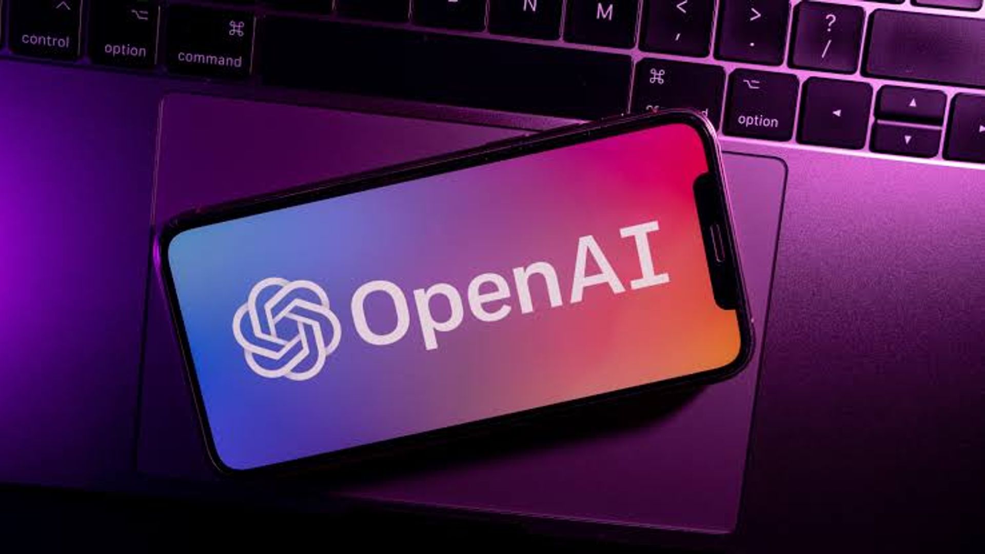 OpenAI logo nutitelefoni ekraanil sülearvuti klaviatuuri ees.